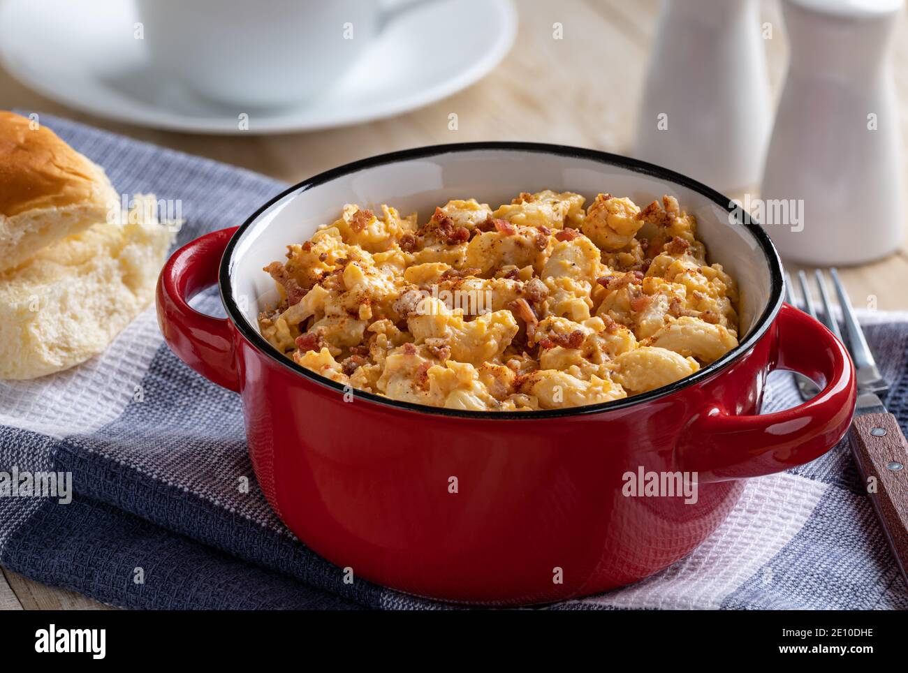 Closeup of a bowl of macaroni and cheese with bacon pieces on wooden table Stock Photo