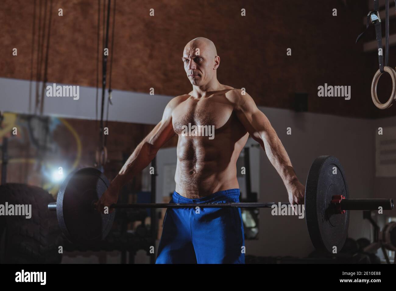 Shirtless muscular mature crossfit athlete working out at the gym
