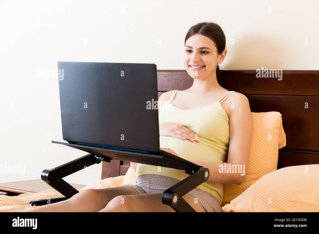 Pregnant Woman Using Laptop Computer in home on bed. Pregnant morning