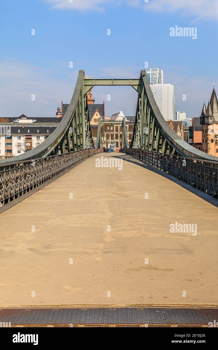 Direct view of the historic pedestrian bridge over the Main in Frankfurt. Houses of the old town in the background with sunshine and a few clouds. Bri Stock Photo