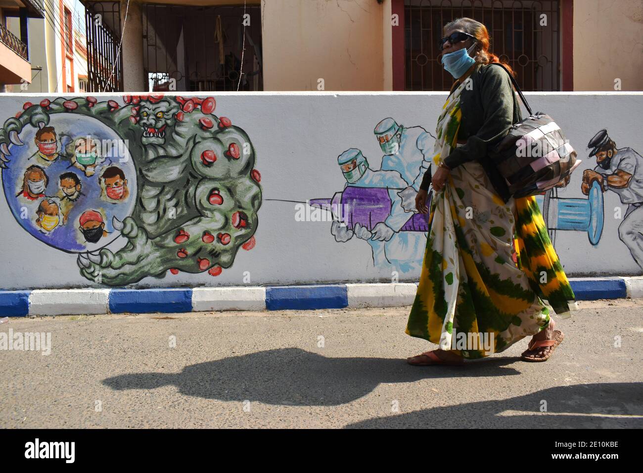 Kolkata, India. 03rd Jan, 2021. (1/3/2021) A woman is passing through in front of a wall graffiti which tell about Front line warriors and the Vaccination in Kolkata. India added 18,177 coronavirus infections in the past 24 hours. India's drugs regulator on Sunday approved Oxford COVID-19 vaccine Covishield, manufactured by the Serum Institute, and indigenously developed Covaxin of Bharat Biotech for restricted emergency use in the country, paving the way for a massive inoculation drive. (Photo by Sudipta Das/Pacific Press/Sipa USA) Credit: Sipa USA/Alamy Live News Stock Photo