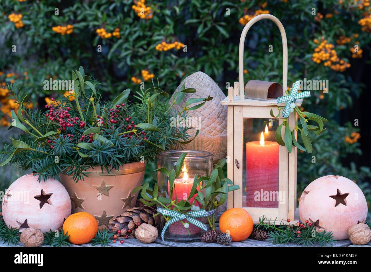 rustic christmas decoration with lantern and bouquet of yew branches, mistletoe and rose hips Stock Photo
