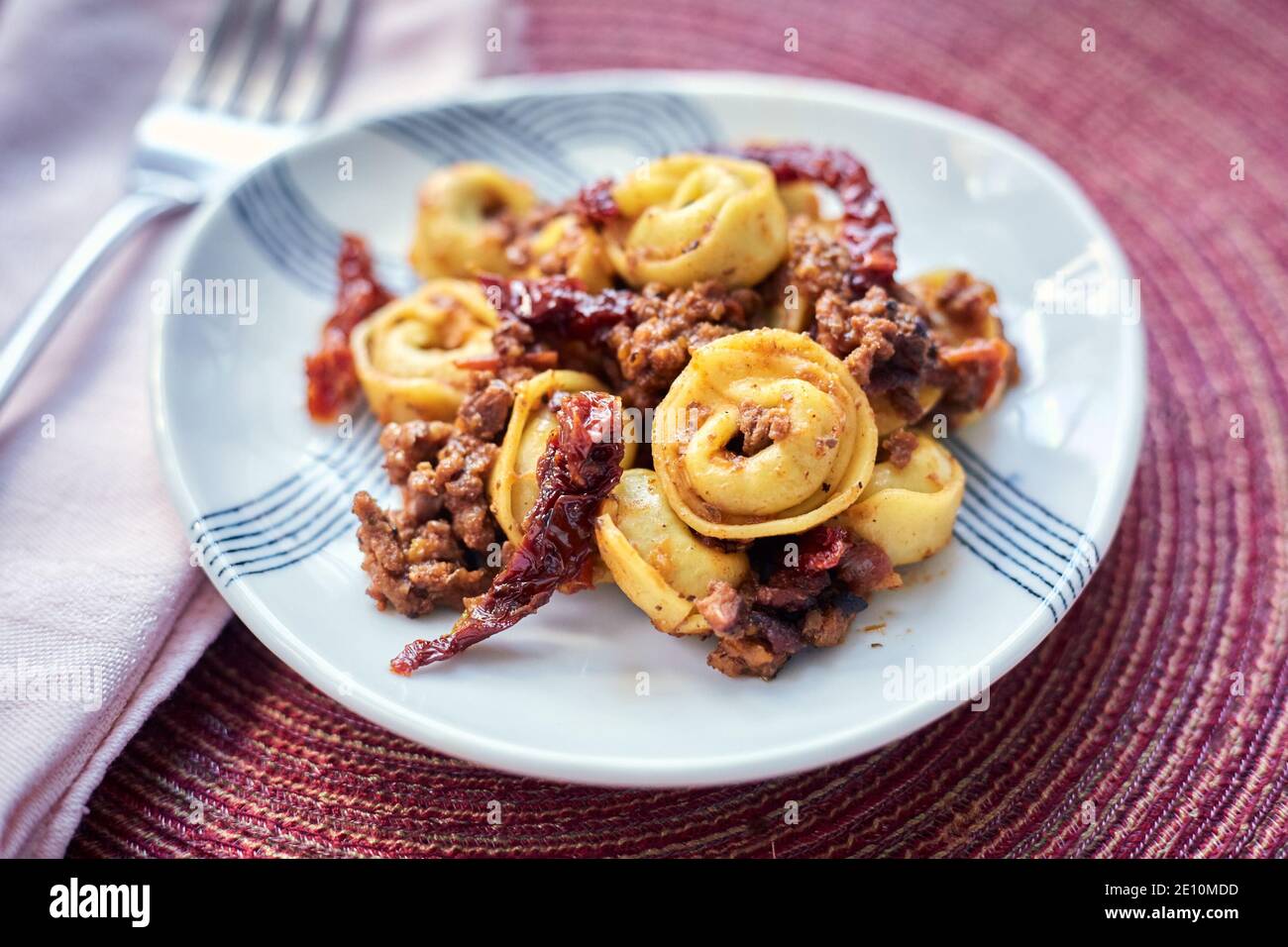 Tortellini with Bolognese Sauce and Sundried Tomatoes with Fork and Napkin, Closeup Side View Stock Photo