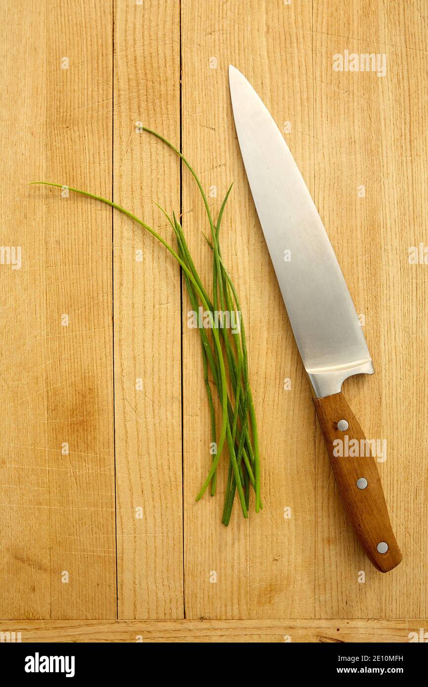 Kitchen Knife with Fresh Chives on Cutting Board Stock Photo