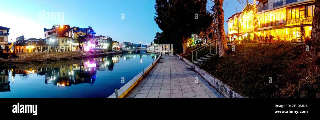 STRUGA, MACEDONIA - JANUARY 1, 2021:: Panoramic image of banks of river Drim and houses in Struga Macedonia with New Year decorative lights Stock Photo