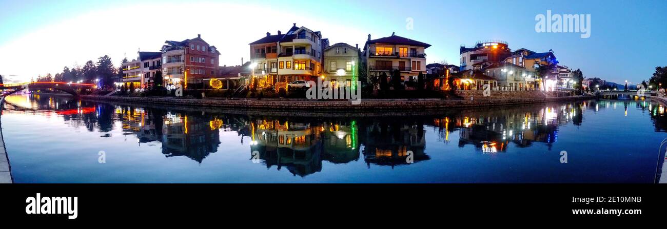 STRUGA, MACEDONIA - JANUARY 1, 2021:: Panoramic image of banks of river Drim and houses in Struga Macedonia with New Year decorative lights Stock Photo