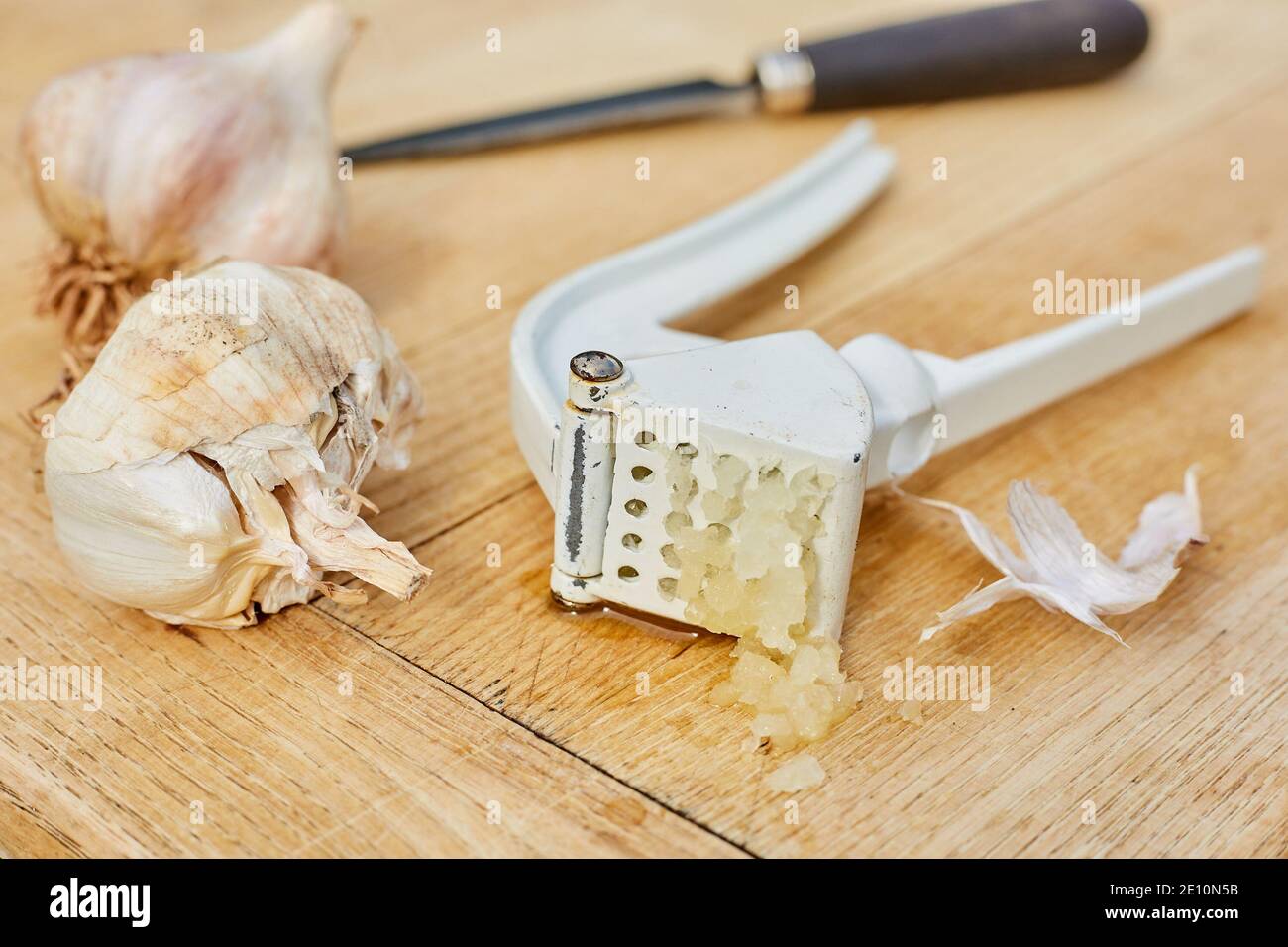 Garlic Bulbs, Knife, and Press on Cutting Board with Freshly Pressed