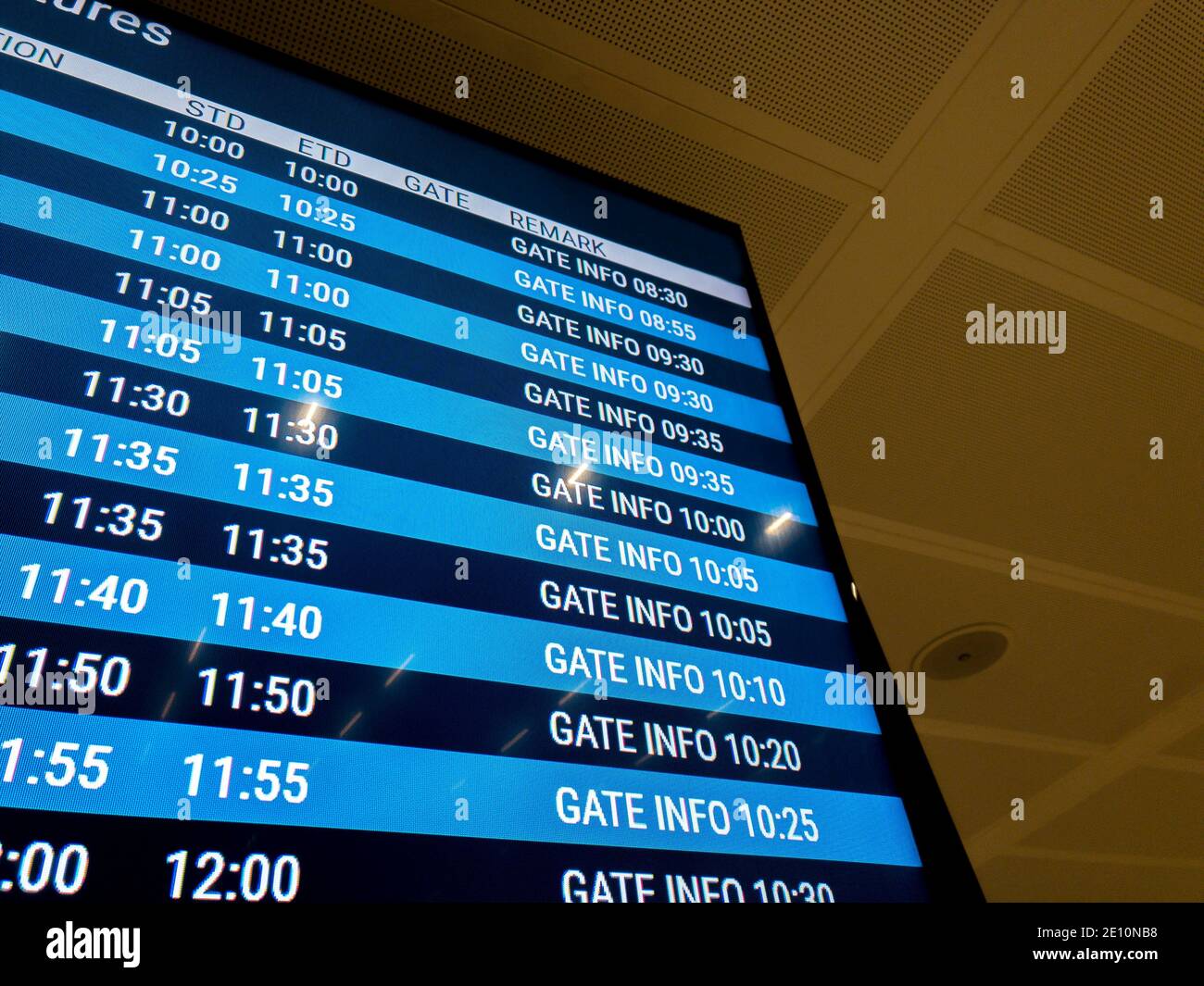 A blue digital screen at an airport announcing time and gate info for each flight. Stock Photo