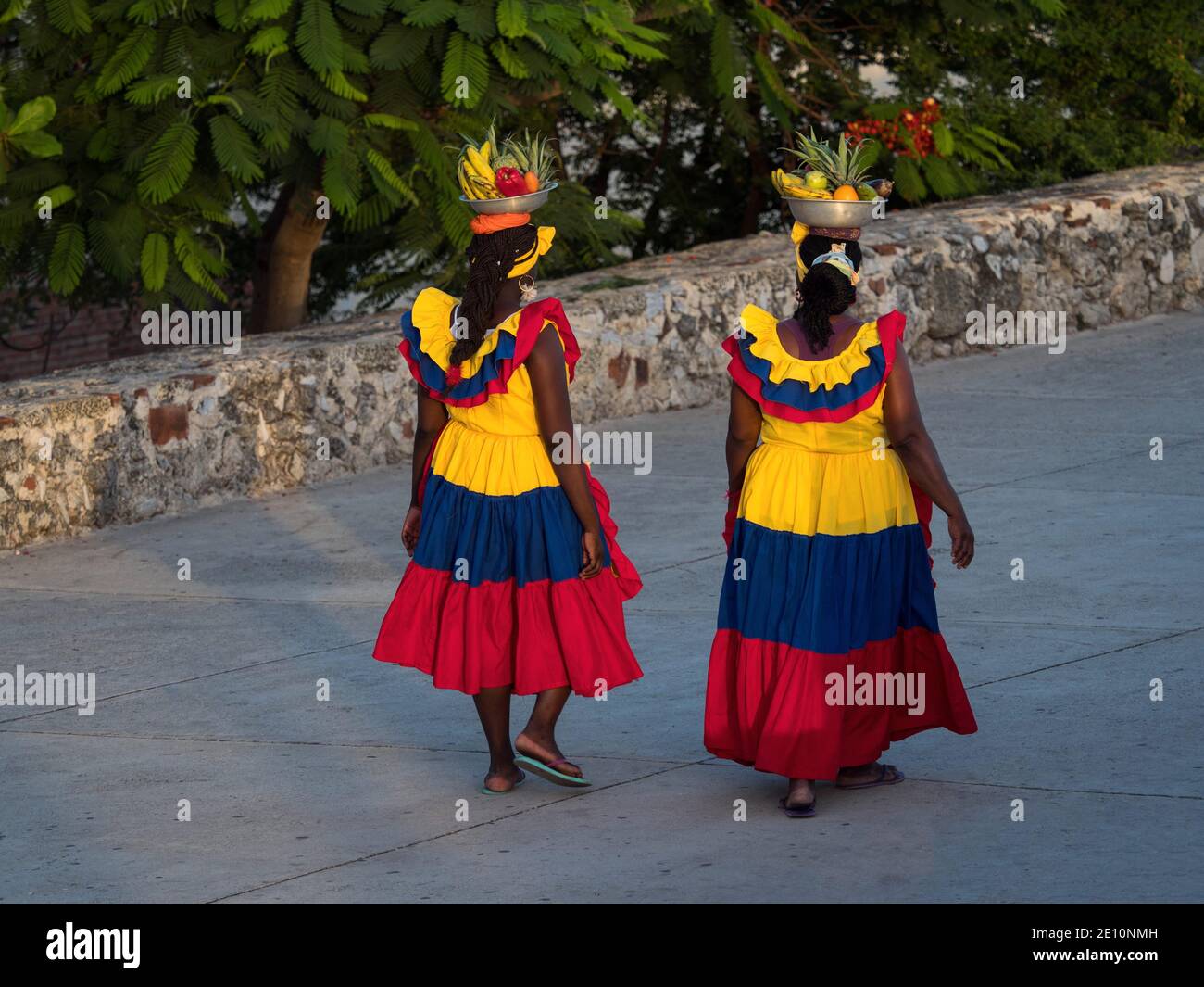 Two afrocolombian women fruit vendor seller colombian national colored dress skirt costume walking in colonial old town of Cartagena de Indias Bolivar Stock Photo
