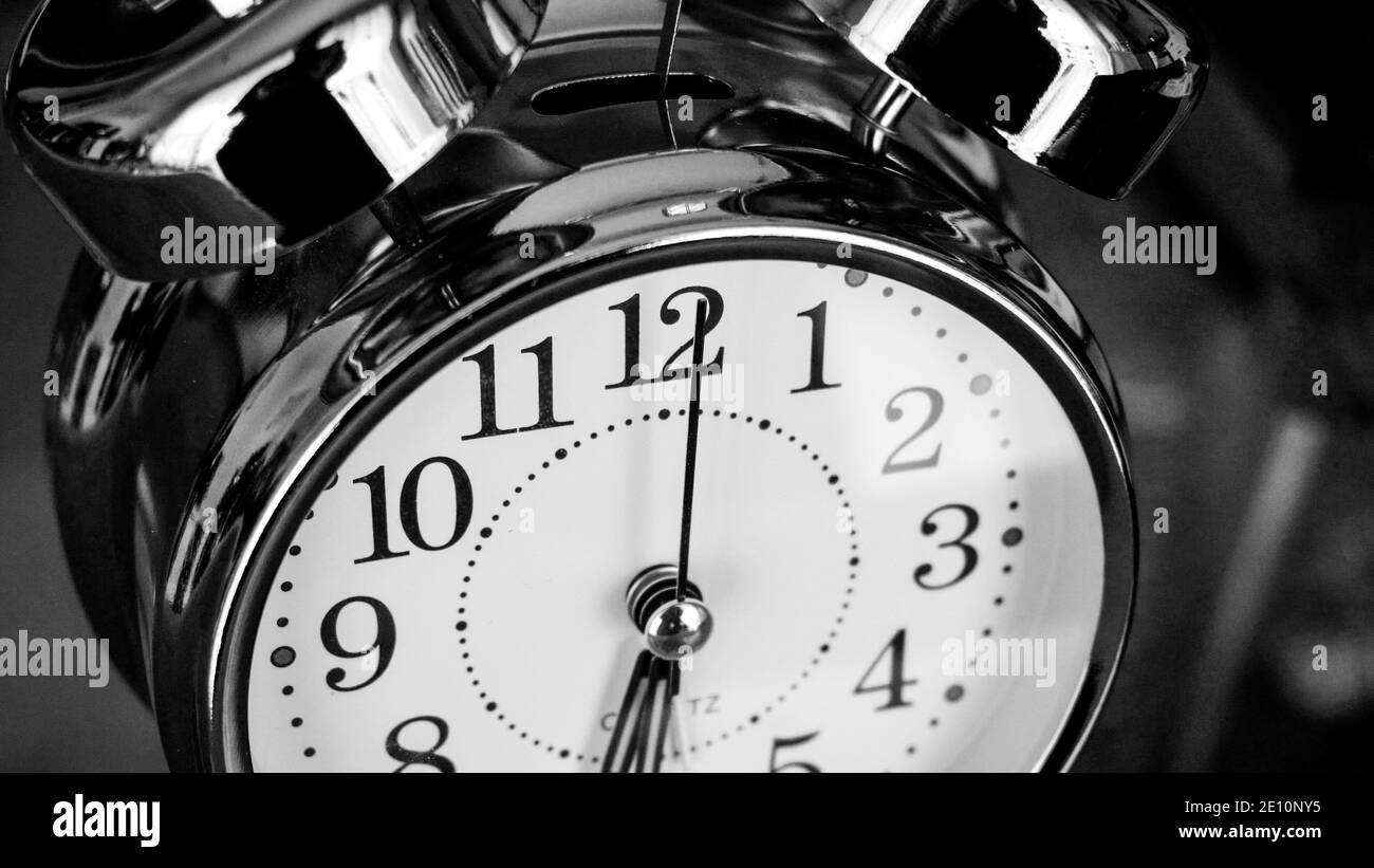 Black white big metallic clock close up. Time or showing time concept. Classic retro mechanical alarm clock with ringer. Time passing or waking up in Stock Photo