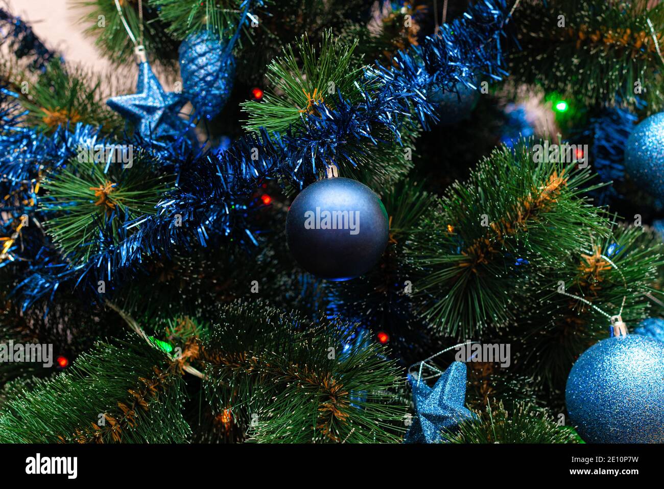 blue Christmas tree toys of various shapes and sizes hang on a green Christmas tree Stock Photo