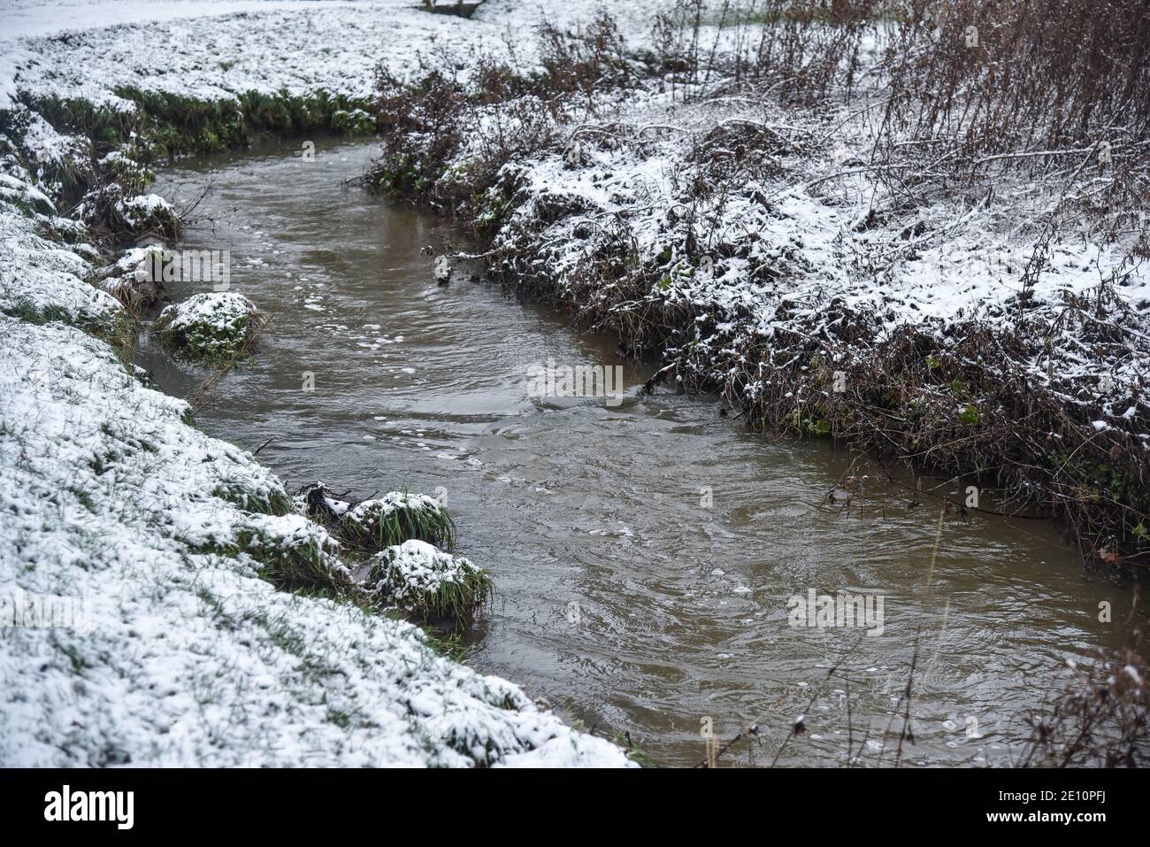 A brook bending or meandering round to the right in a sowy park in Uttoxeter England Stock Photo