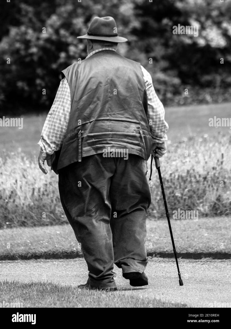 Baggy Trousers. Smartly dressed rural senior adult, overwieight with baggy trousers and waistcaot  and stick in mid step Stock Photo