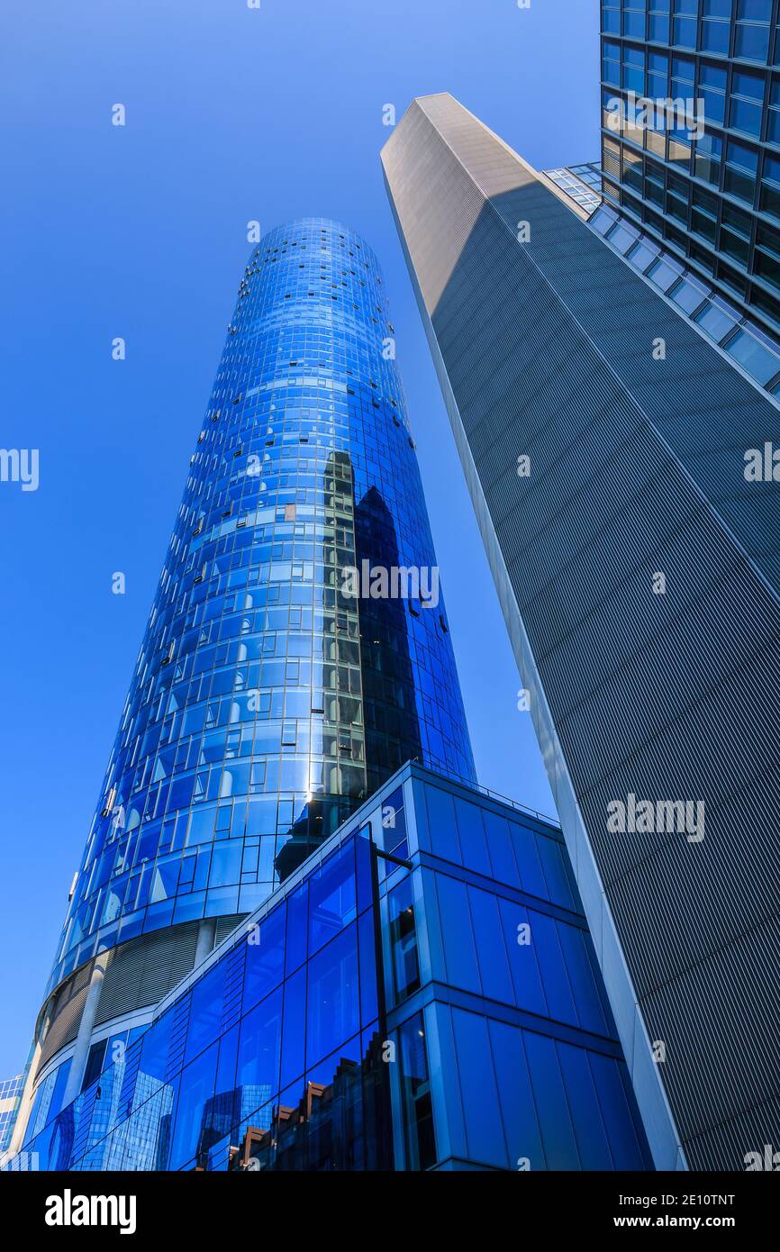 Skyscrapers and skyscrapers looking upwards. Window facade of commercial buildings in Frankfurt Main. Blue sky in sunny day. Reflections in the glass Stock Photo