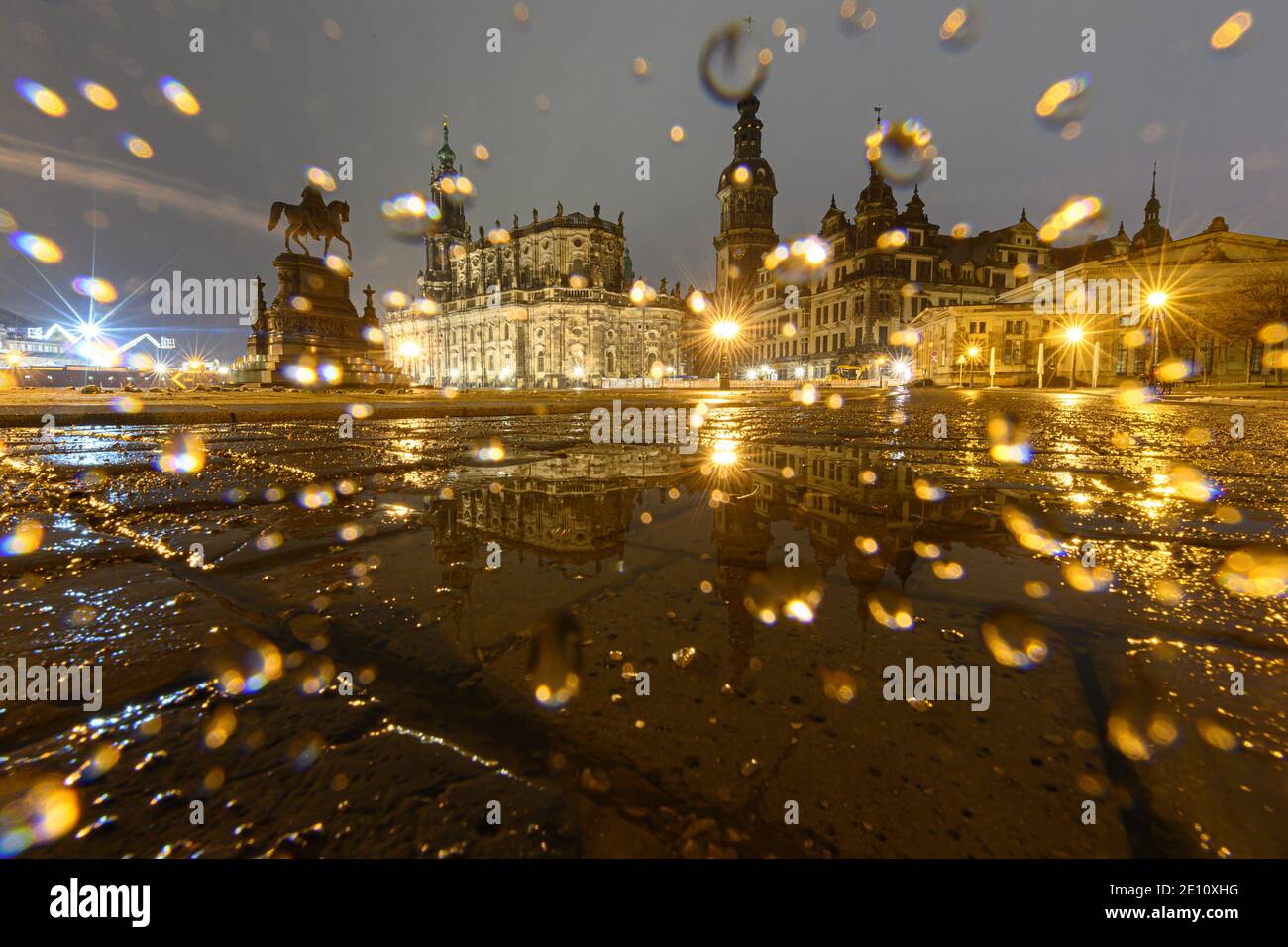 Dresden, Germany. 03rd Jan, 2021. The equestrian statue of King Johann (l-r), the Hofkirche, the Hausmannsturm, the Residenzschloss and the Schinkelwache are reflected in a puddle on Theaterplatz in the evening. Credit: Robert Michael/dpa-Zentralbild/dpa/Alamy Live News Stock Photo