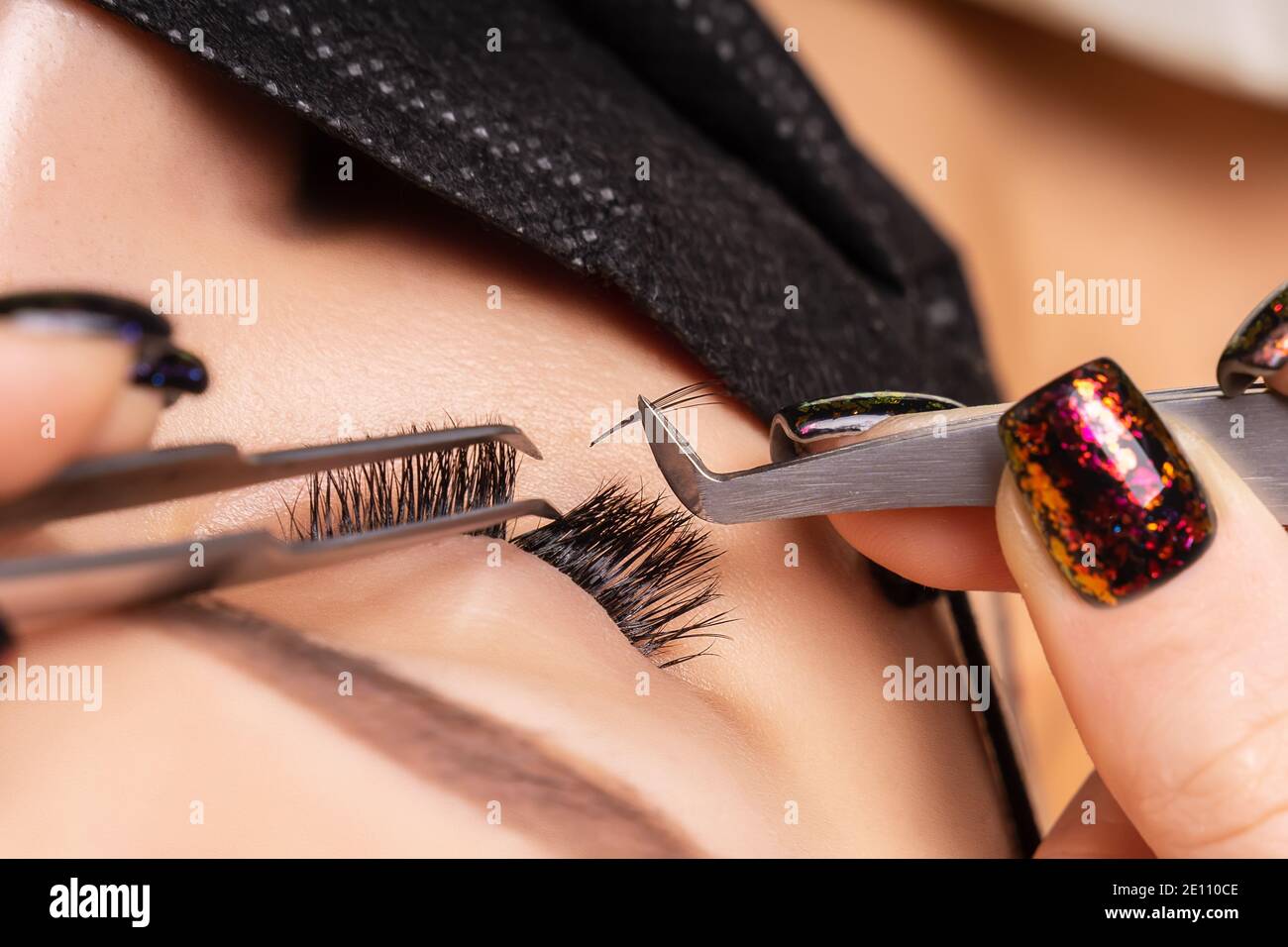 Eyelash Extension Procedure. Beautiful Woman with Extreme Long False Eyelashes. Makeup, Cosmetics. Beauty, Skincare. Woman in medical mask. Stock Photo