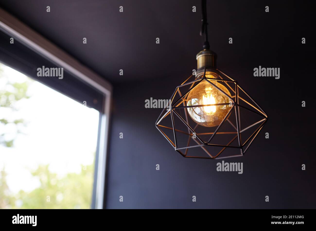 Loft style light bulb glowing near window. Warm light. Coffee shop ...