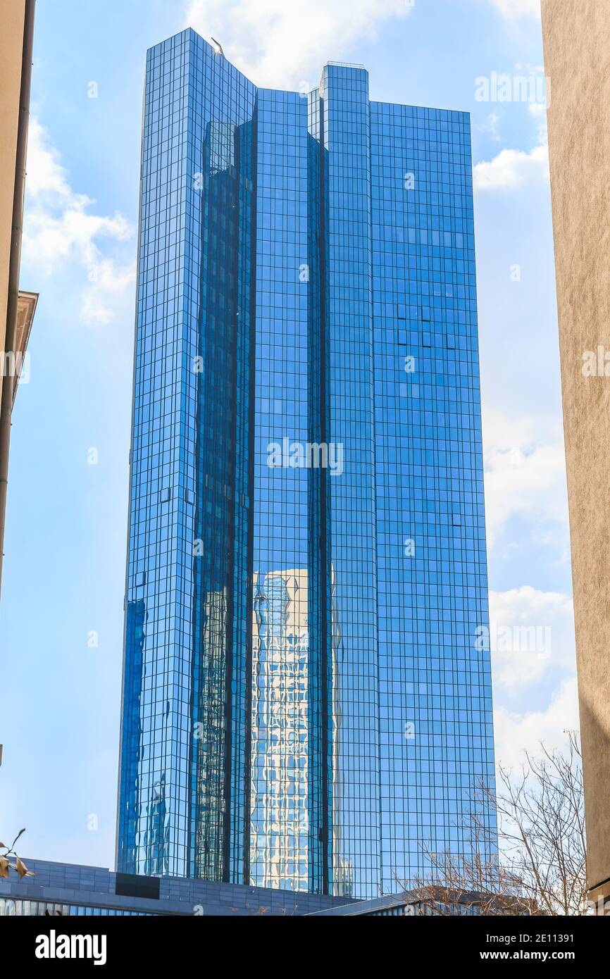 Skyscraper with glass facade in sunshine and blue sky with clouds. Skyscraper in the financial and business district of Frankfurt. Reflections on the Stock Photo