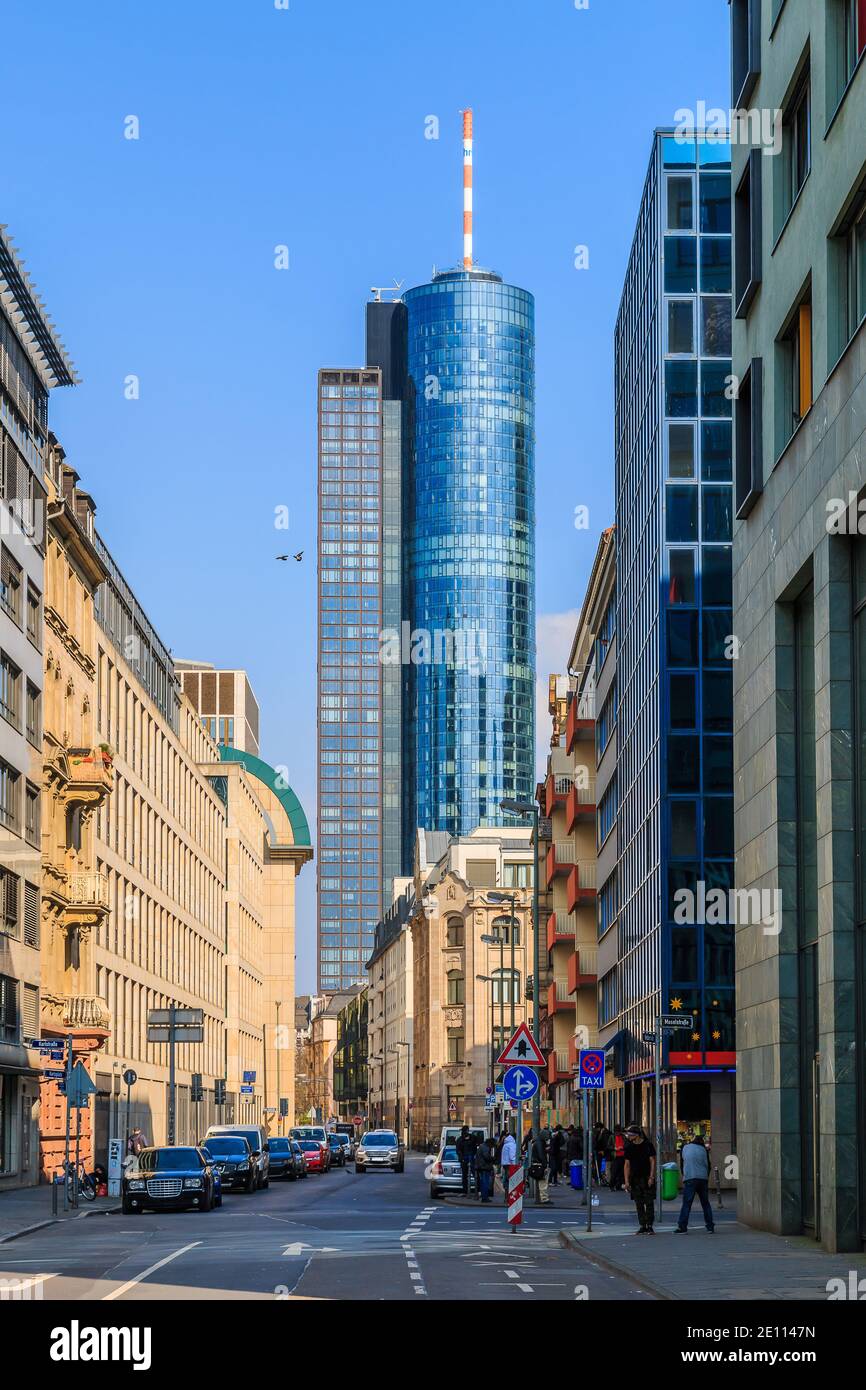 Street with cars in the city of Frankfurt. Commercial buildings along the street with a view of a skyscraper. High-rise building with glass facade in Stock Photo