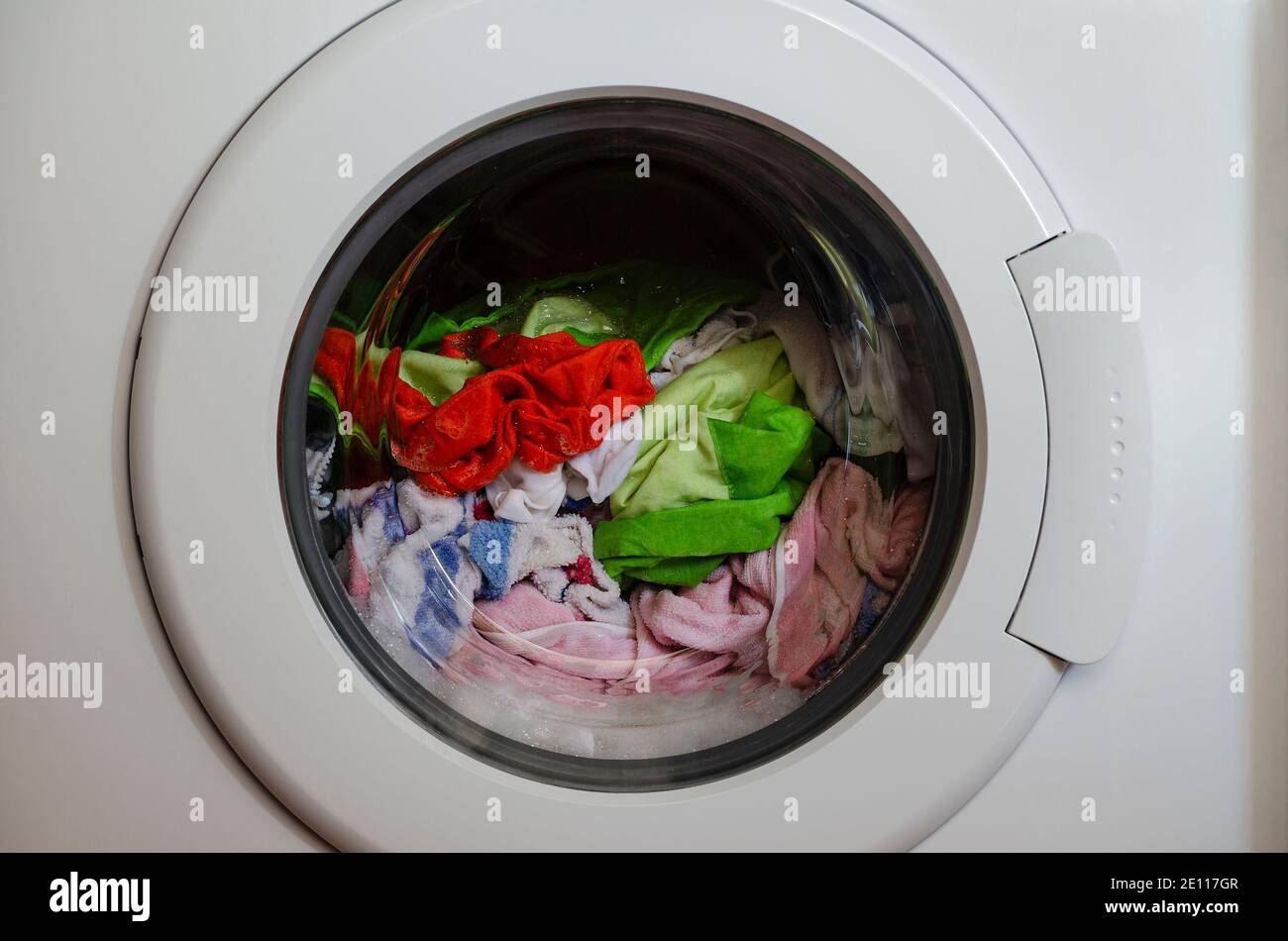 Washing machine door with rotating garments inside Stock Photo Alamy