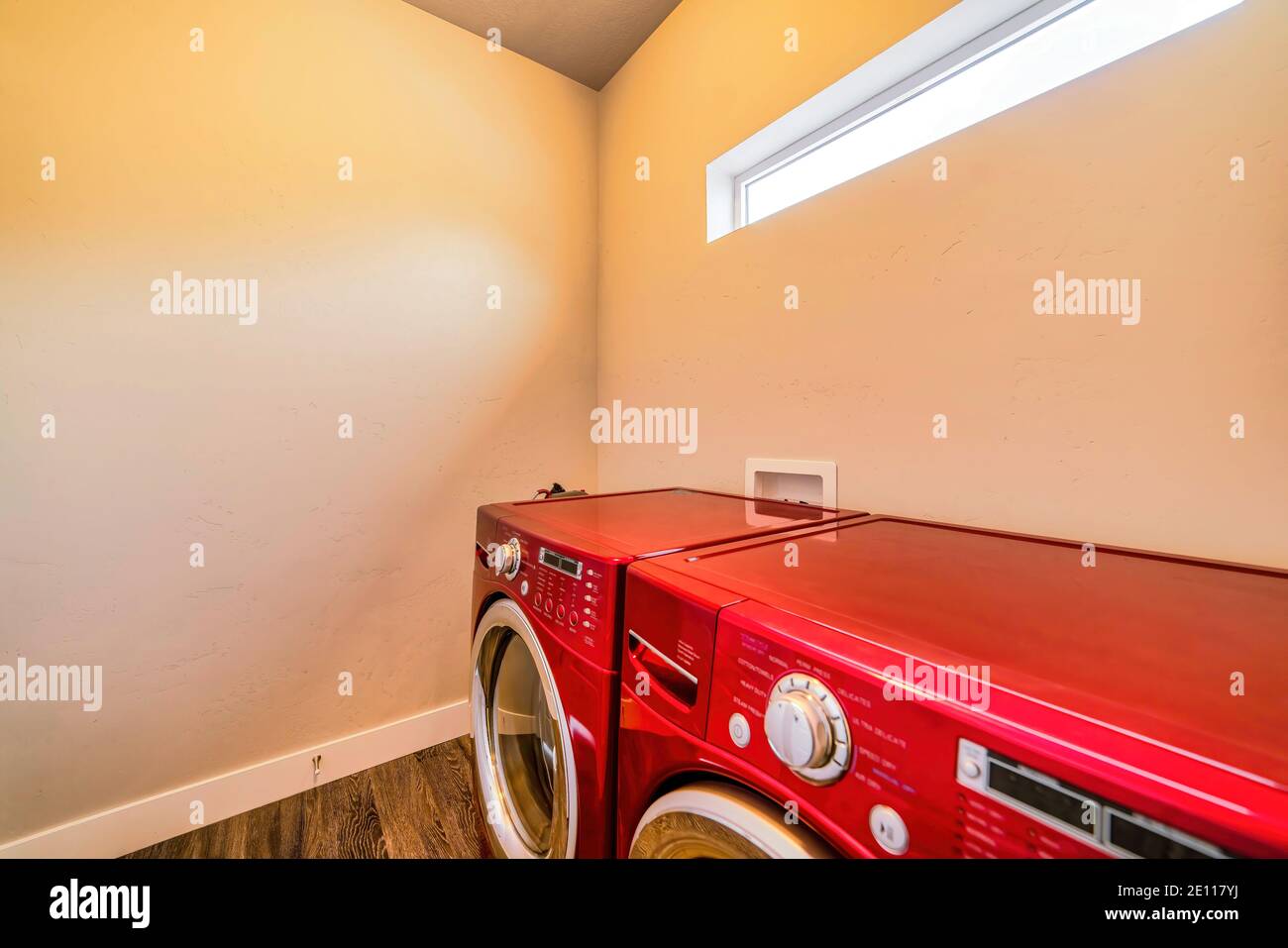 Bright red washing machine and clothes dryer inside the laundry room of home Stock Photo