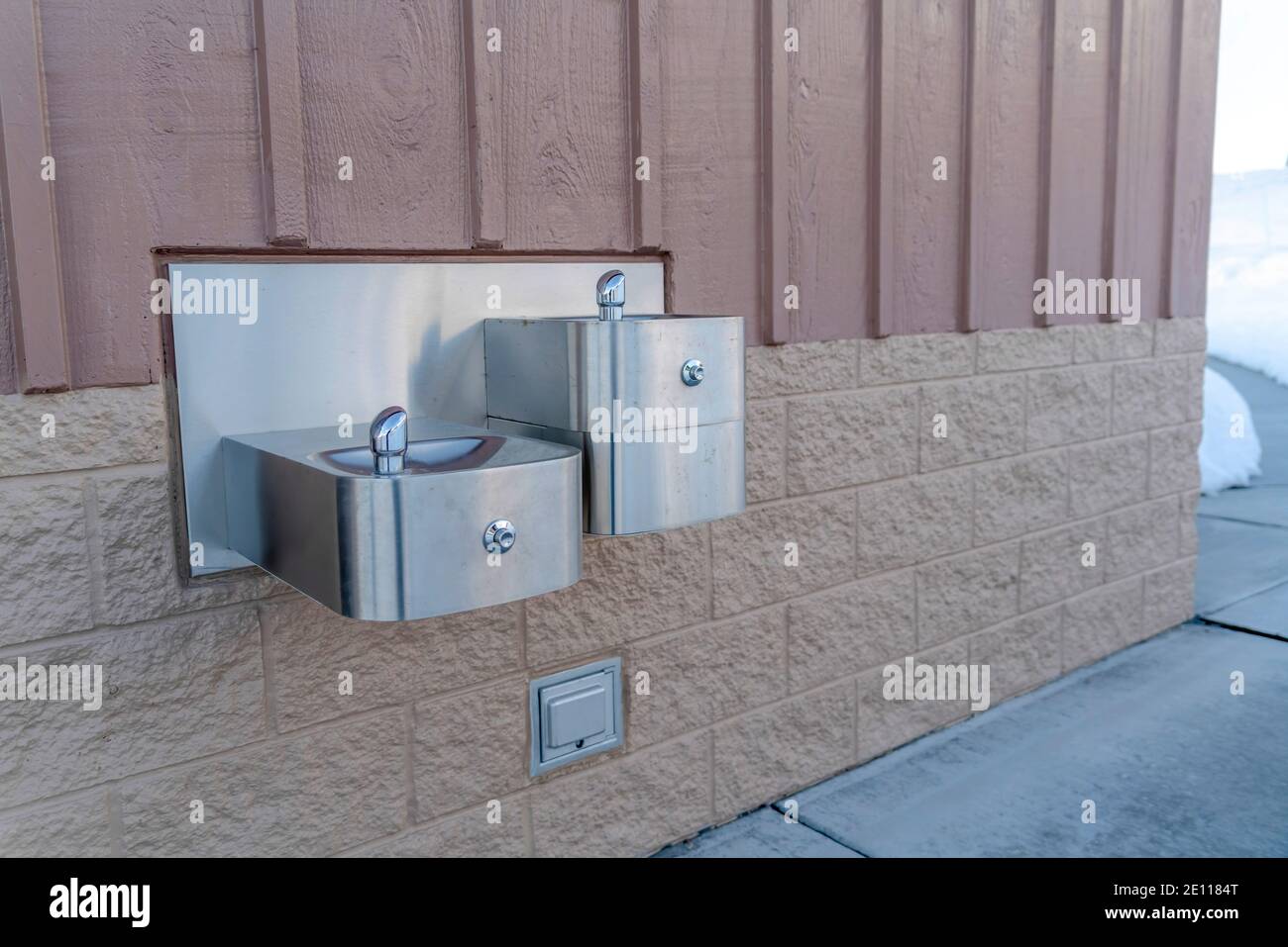 Drinking fountain for children and adults mounted on exterior wall of