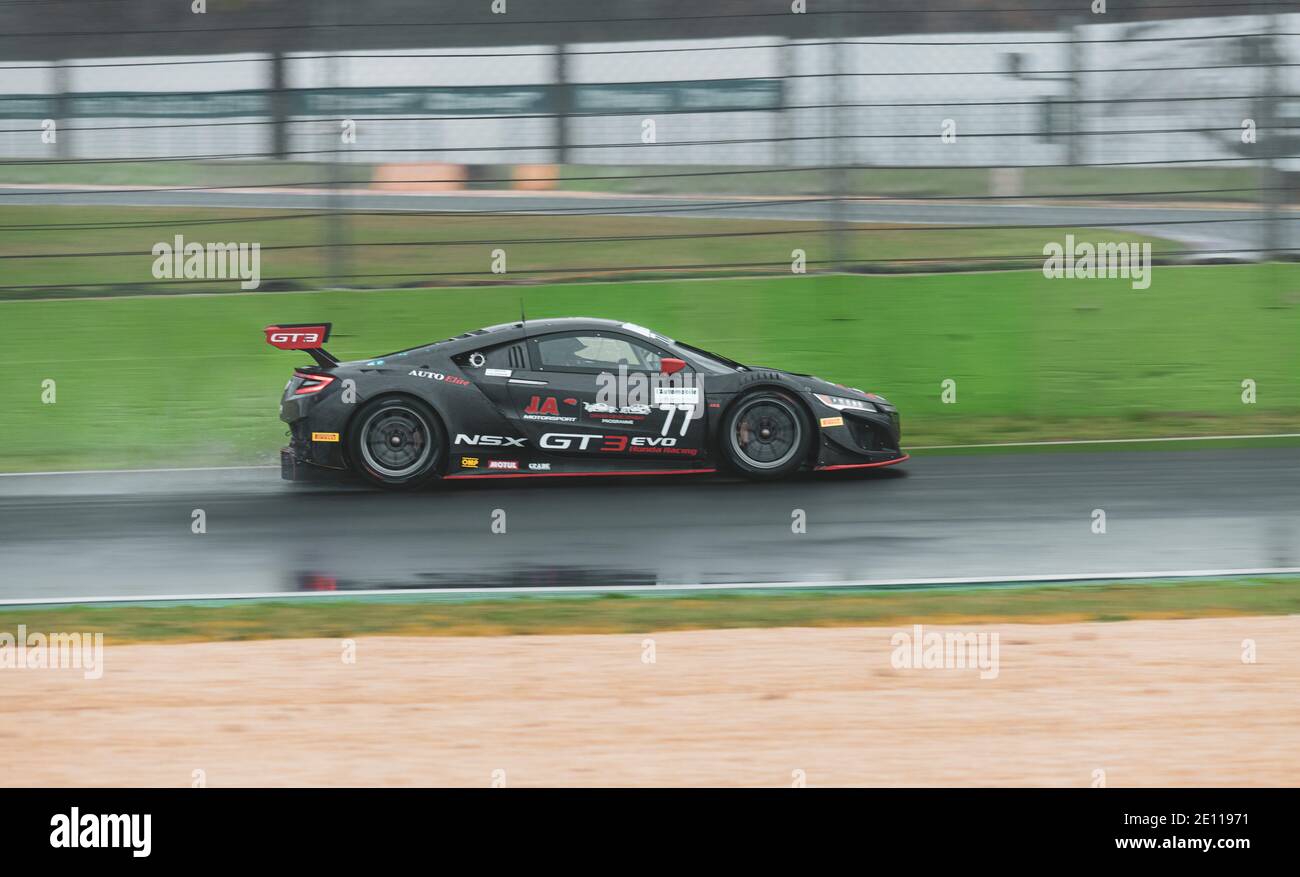 Supercar Honda racing action on wet raining asphalt track circuit spraying water Stock Photo