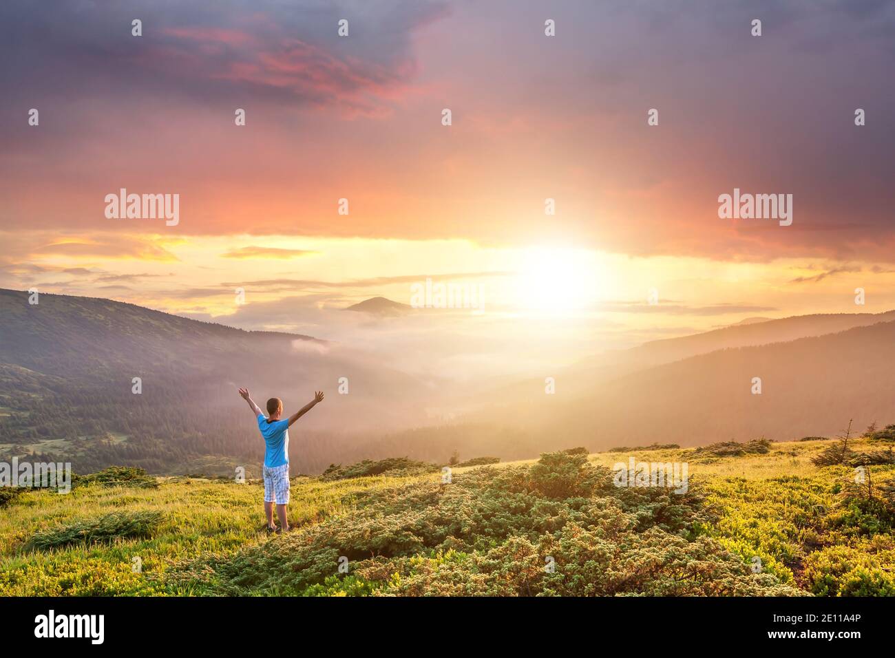 Hiker man standing on top of a mountain with raised hands and enjoying ...