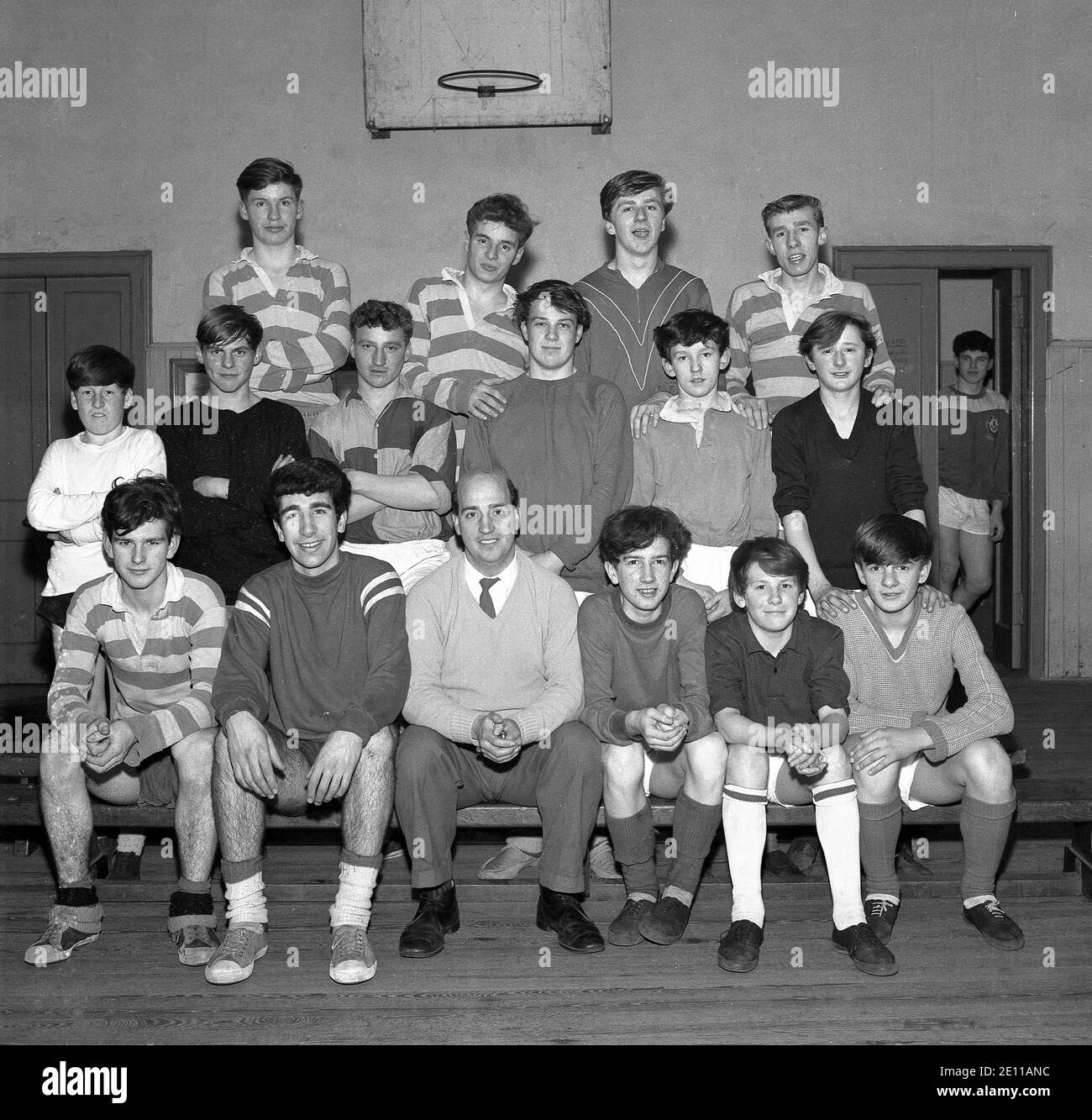 1960s, historical, younger and older male members of the Bowill Youth Club, in their PE kit sit and stand together, with the Youth Club team leader in the sports hall, for a group photo, Fife, Scotland, UK. Stock Photo