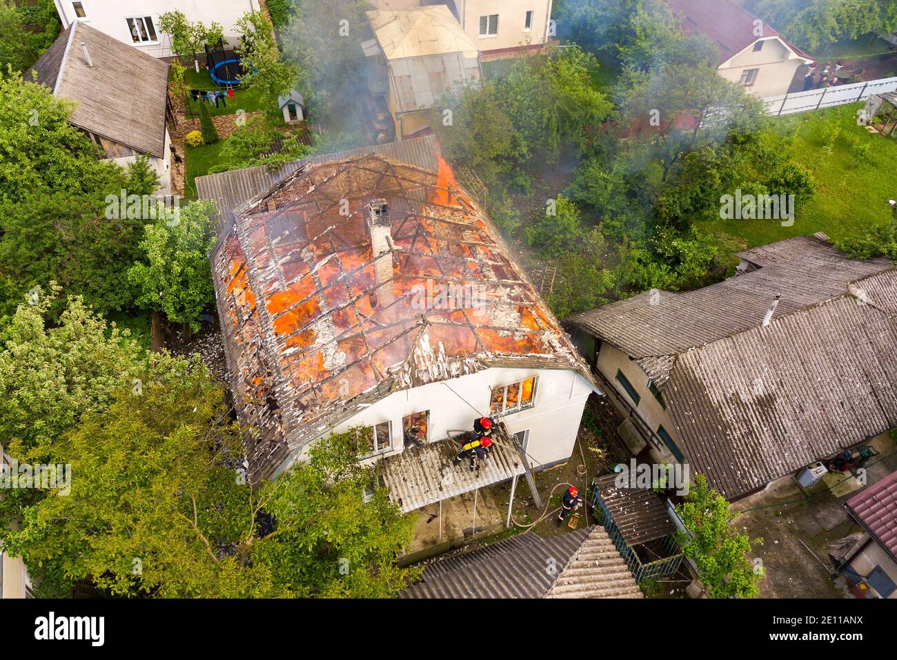 Aerial view of a house on fire with orange flames and white thick smoke ...