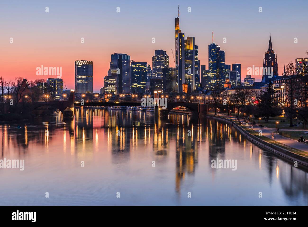 Frankfurt skyline in the evening at sunset. High-rise buildings from the financial district and river Main with reflections. Illuminated houses Stock Photo