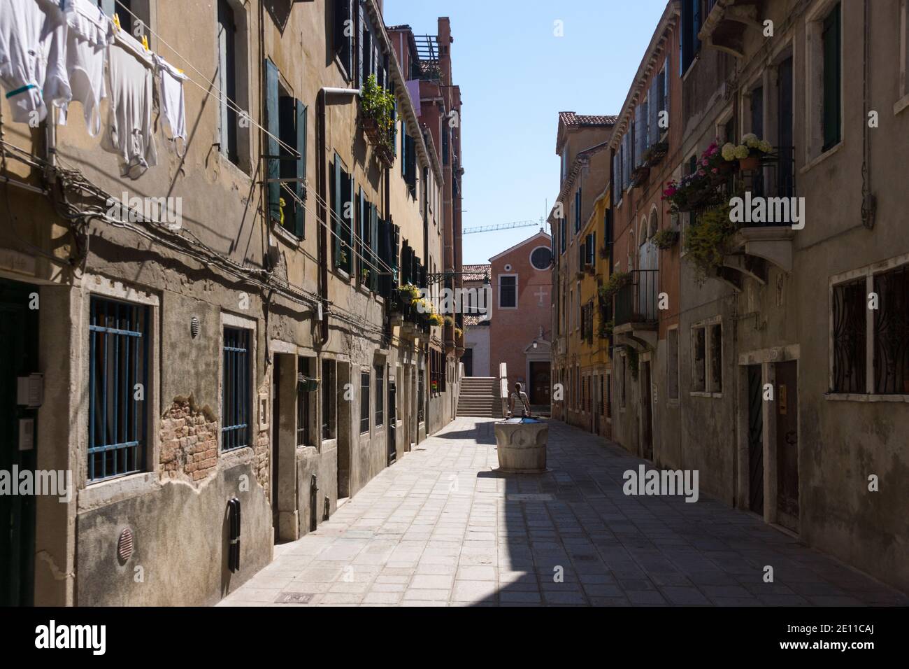 A lone tourist walking down the Ruga Vecchia - an example of how deserted side and back streets in Venice are when you're off the beaten path. Italy Stock Photo