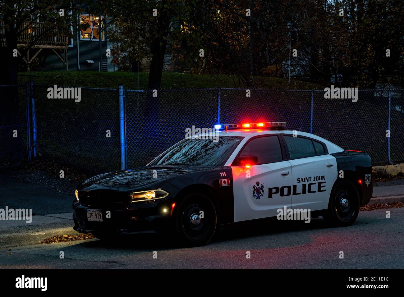Saint John, NB, Canada - October 31, 2020: A police car at the side of the road after sunset. The red and blue lights are illuminated. Stock Photo