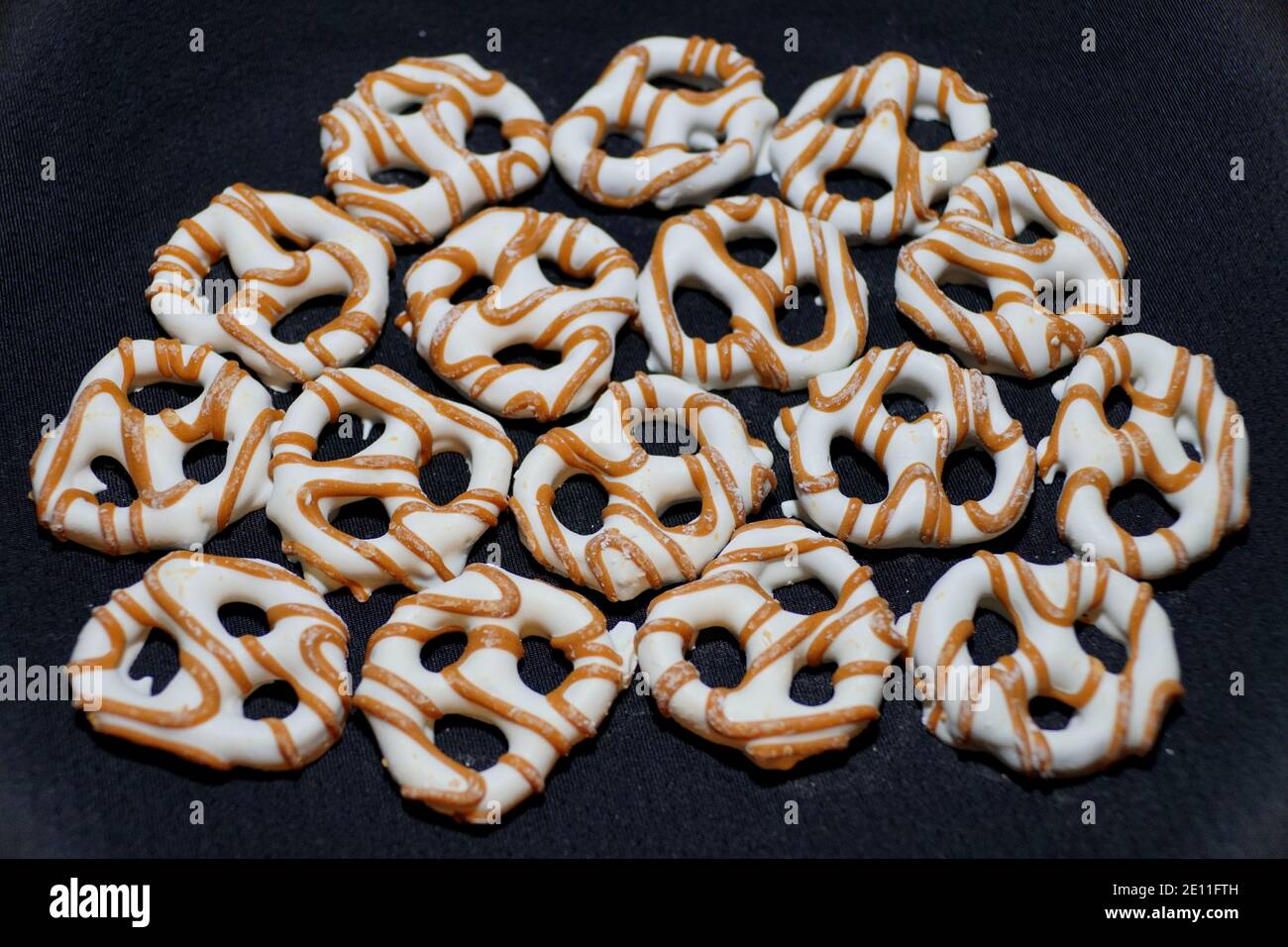 Yogurt pretzels with caramel drizzles on a black isolated background Stock Photo