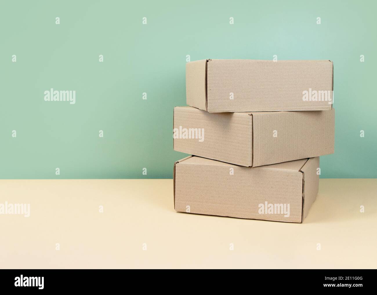 Stack of Brown cardboard boxes on mint background. Blank carton box