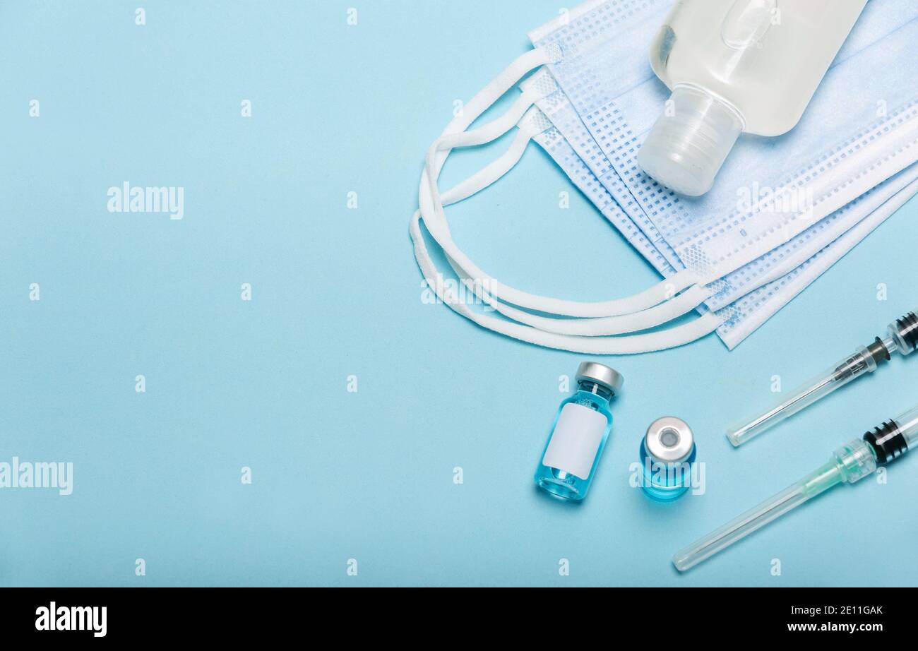 Medical bottle, hand sanitizer, vials, syringes and face mask on blue ...