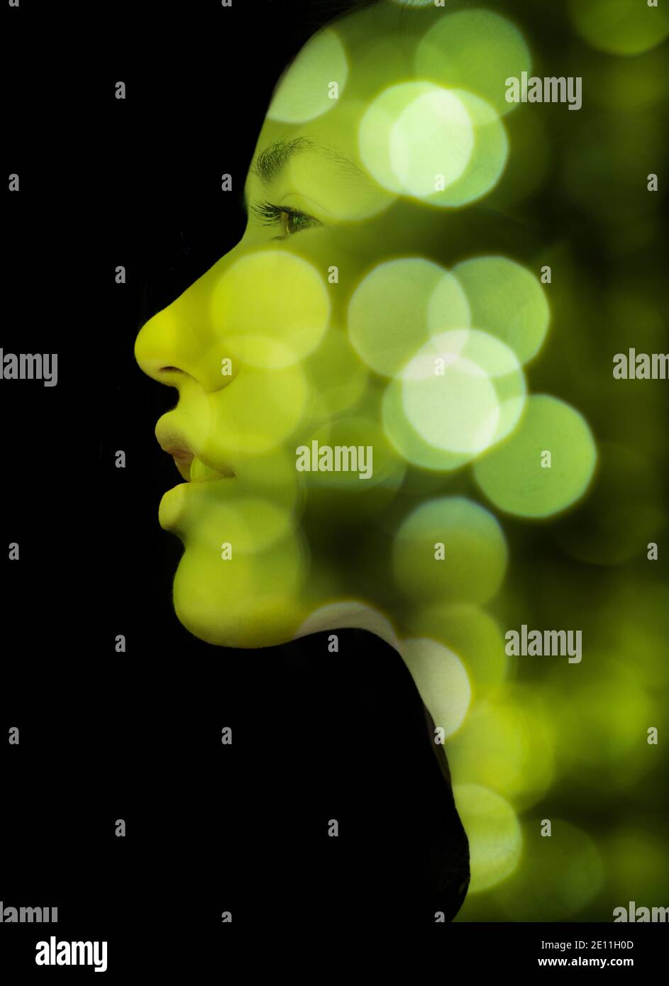 A double exposure portrait of a young woman's profile against black ...