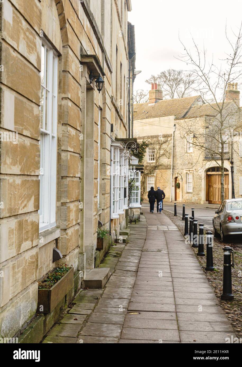 Two men walk down Park Street lined with stone cottages, Woodstock, Oxfordshire. Winter 2020 Stock Photo