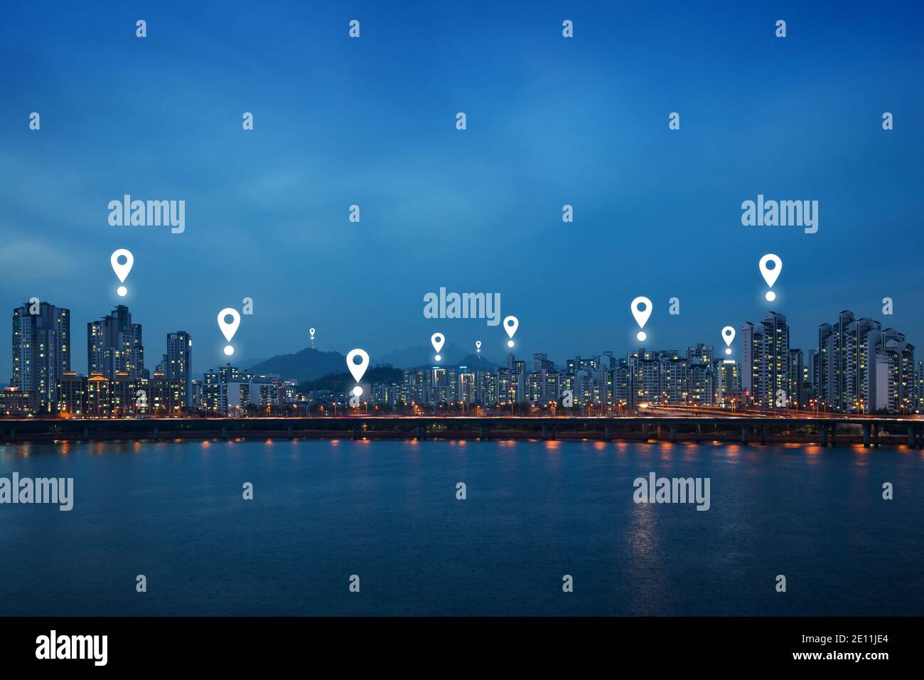 Map pin icons on Seoul cityscape at dusk. Lit residential district and bridge along the Han River in Seoul, South Korea, at night. Copy space. Stock Photo
