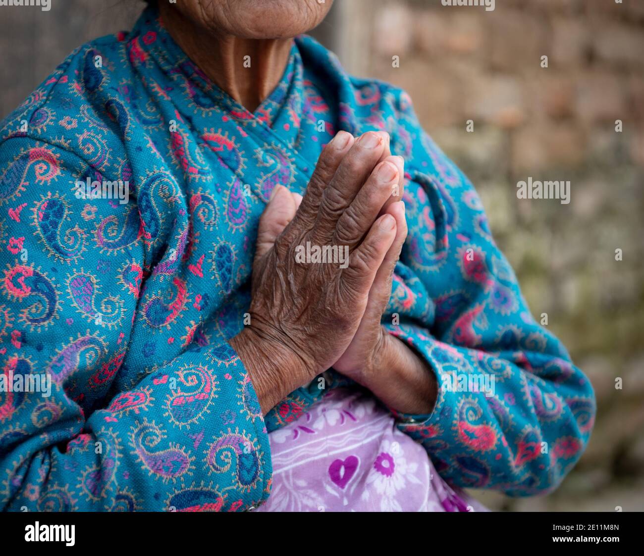Unrecognized elder woman wearing blue cloths crossing her wrinkled hands. Aging age process Stock Photo
