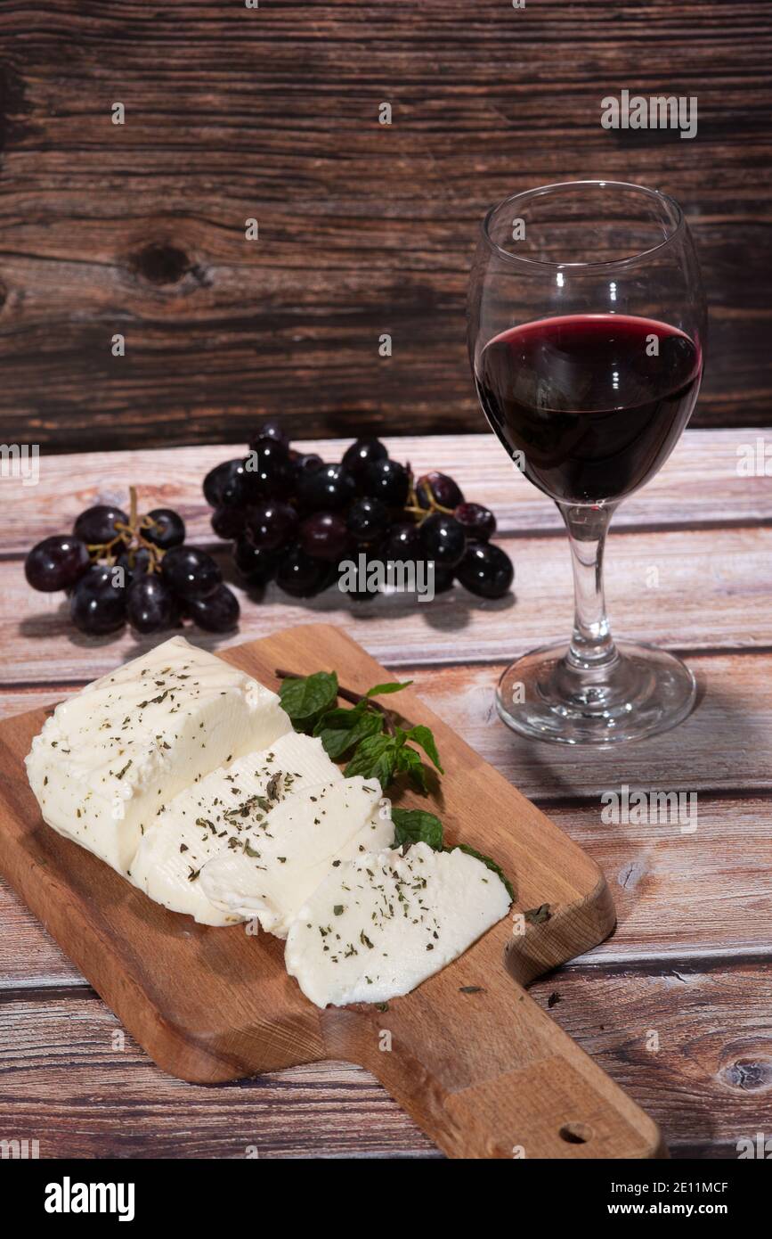 Slices of cyprus halloumi cheese red wine and grapes on a table Stock Photo