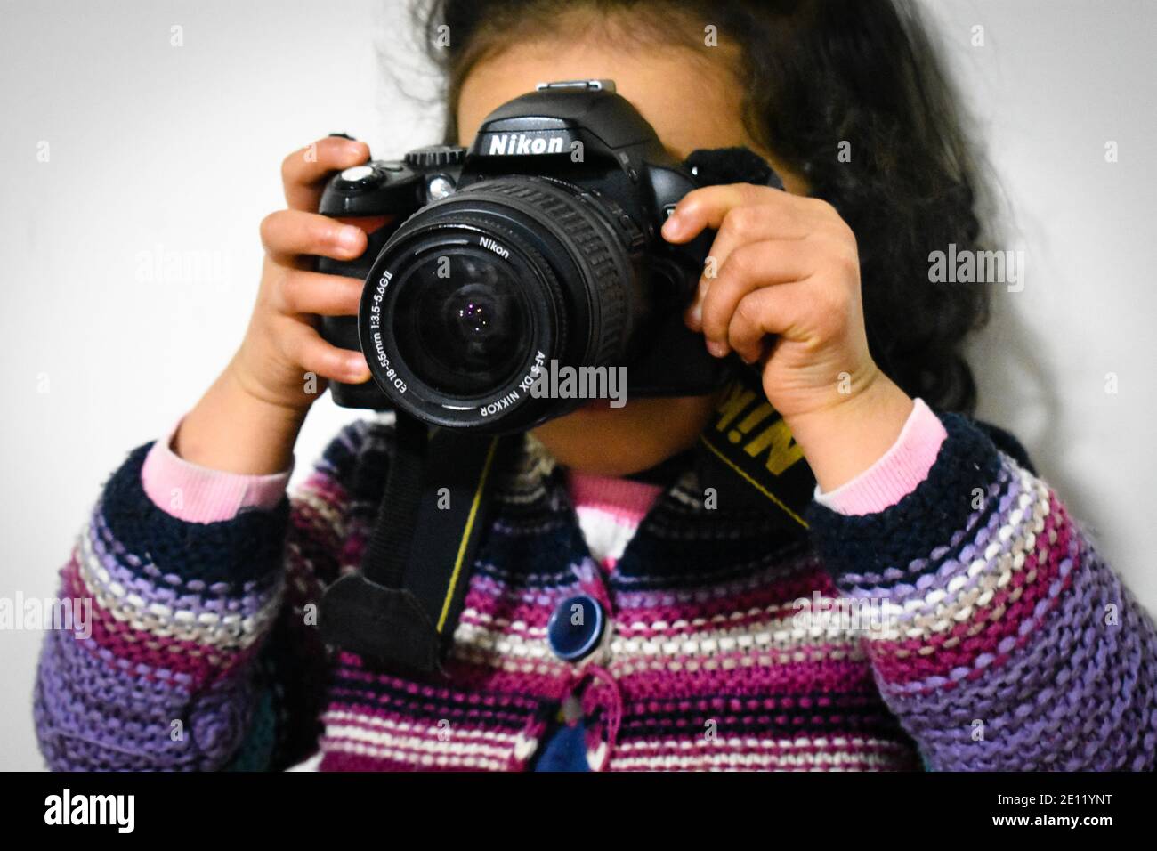 girl holding a camera against a white wall Stock Photo