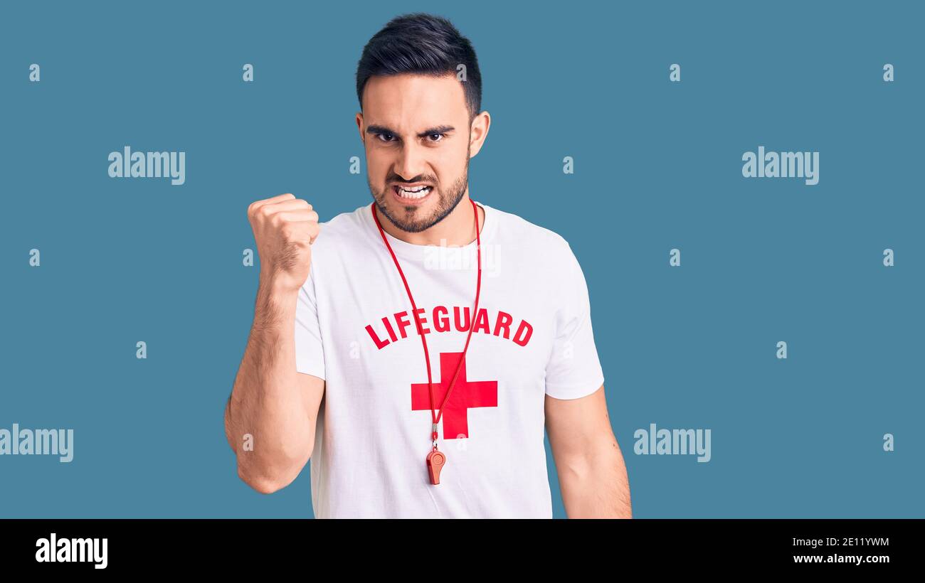 Young handsome man wearing lifeguard uniform angry and mad raising fist