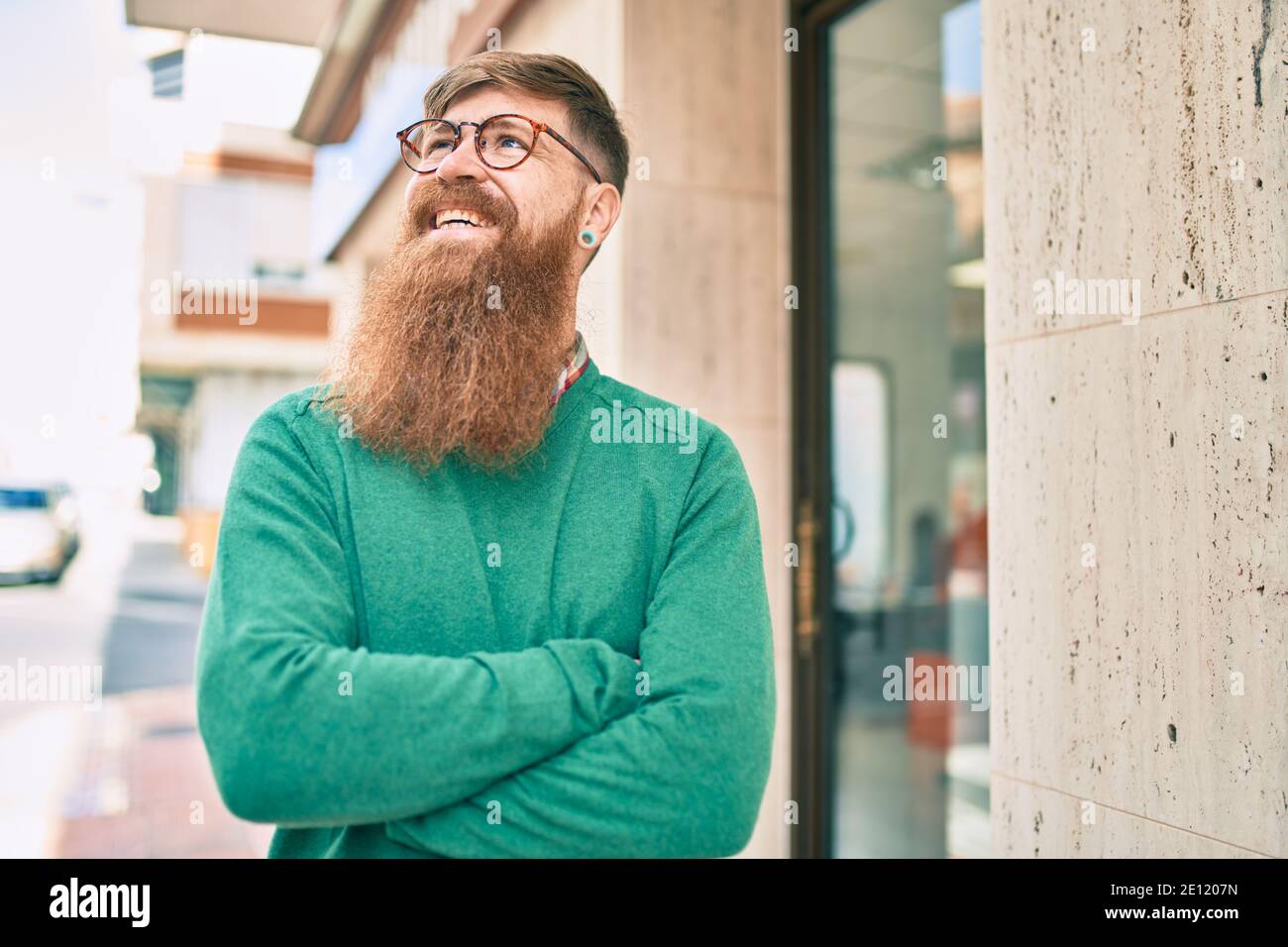 Young irish man with arms crossed smiling happy walking at the city. Stock Photo