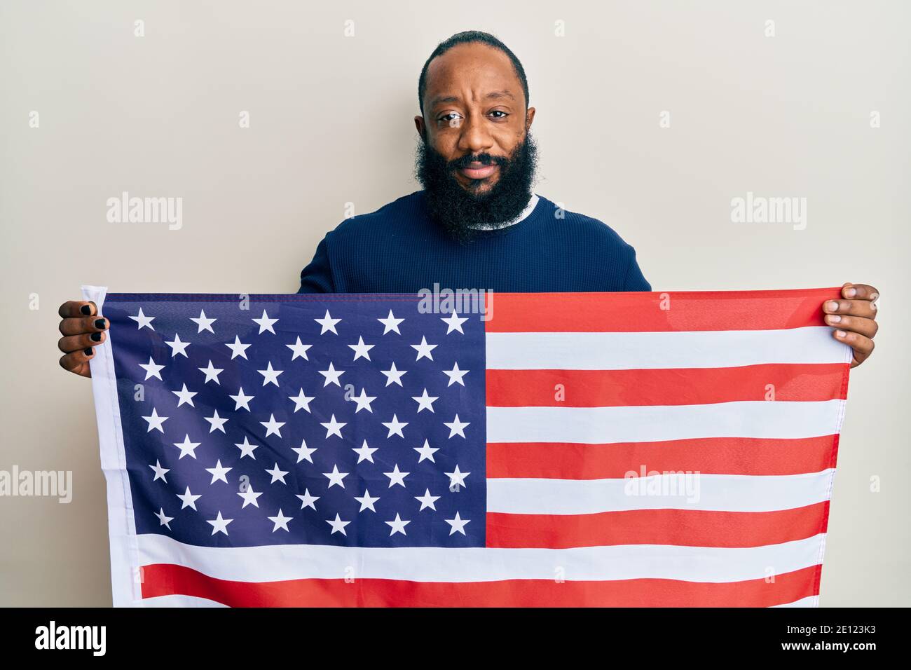 Young african american man holding united states flag relaxed with ...