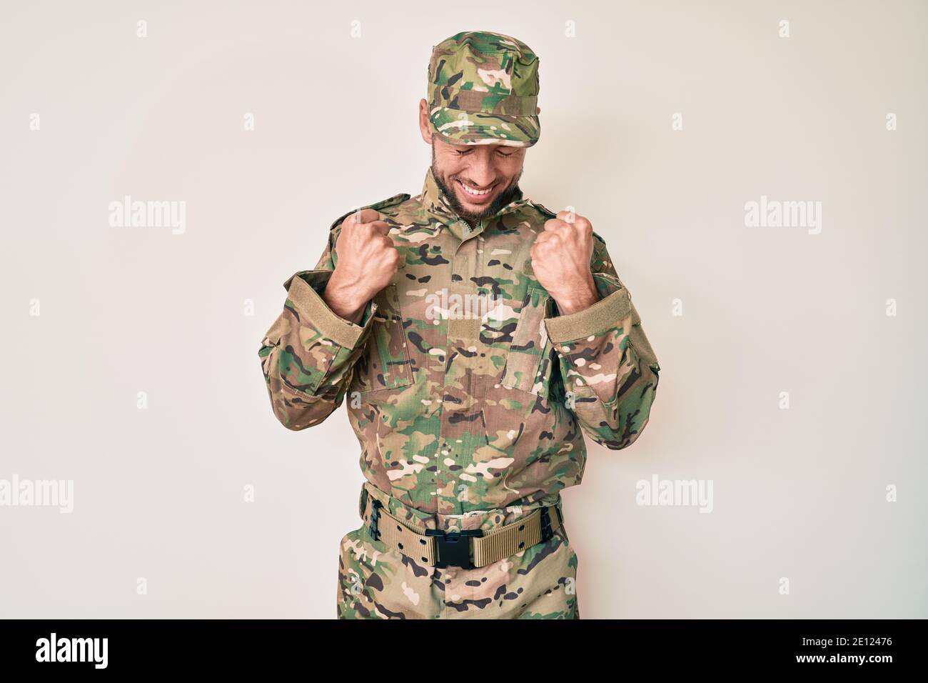 Young caucasian man wearing camouflage army uniform excited for success ...