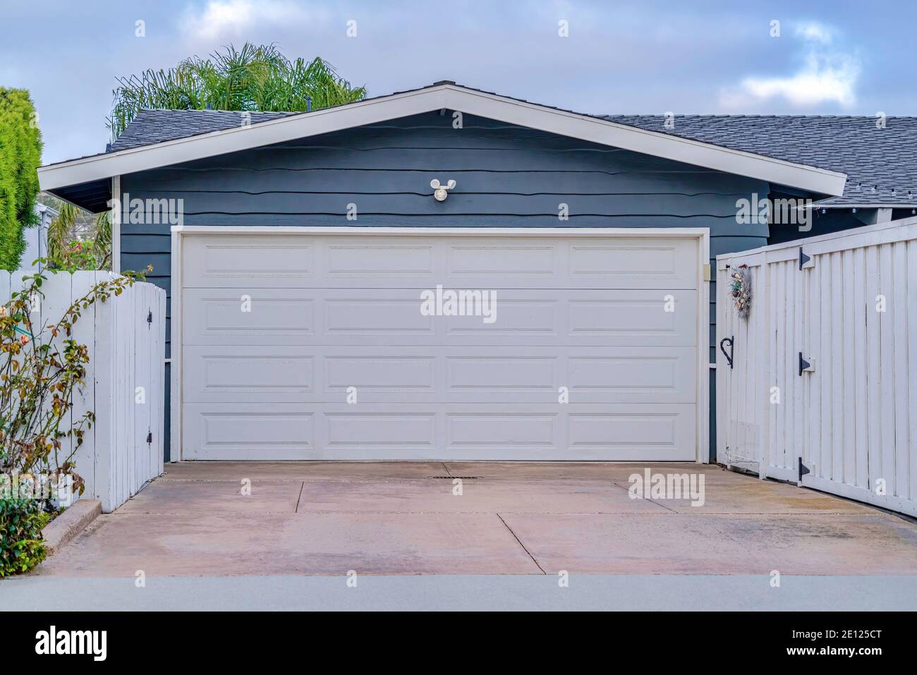 Garage with gable roof over white door and gray wall in San Diego