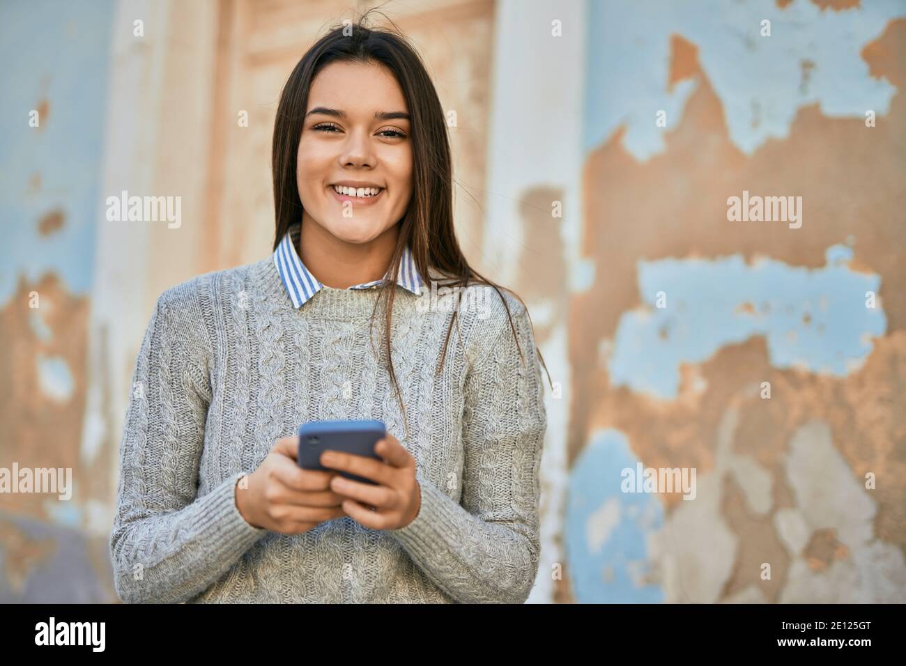Young hispanic girl smiling happy using smartphone at the city Stock ...