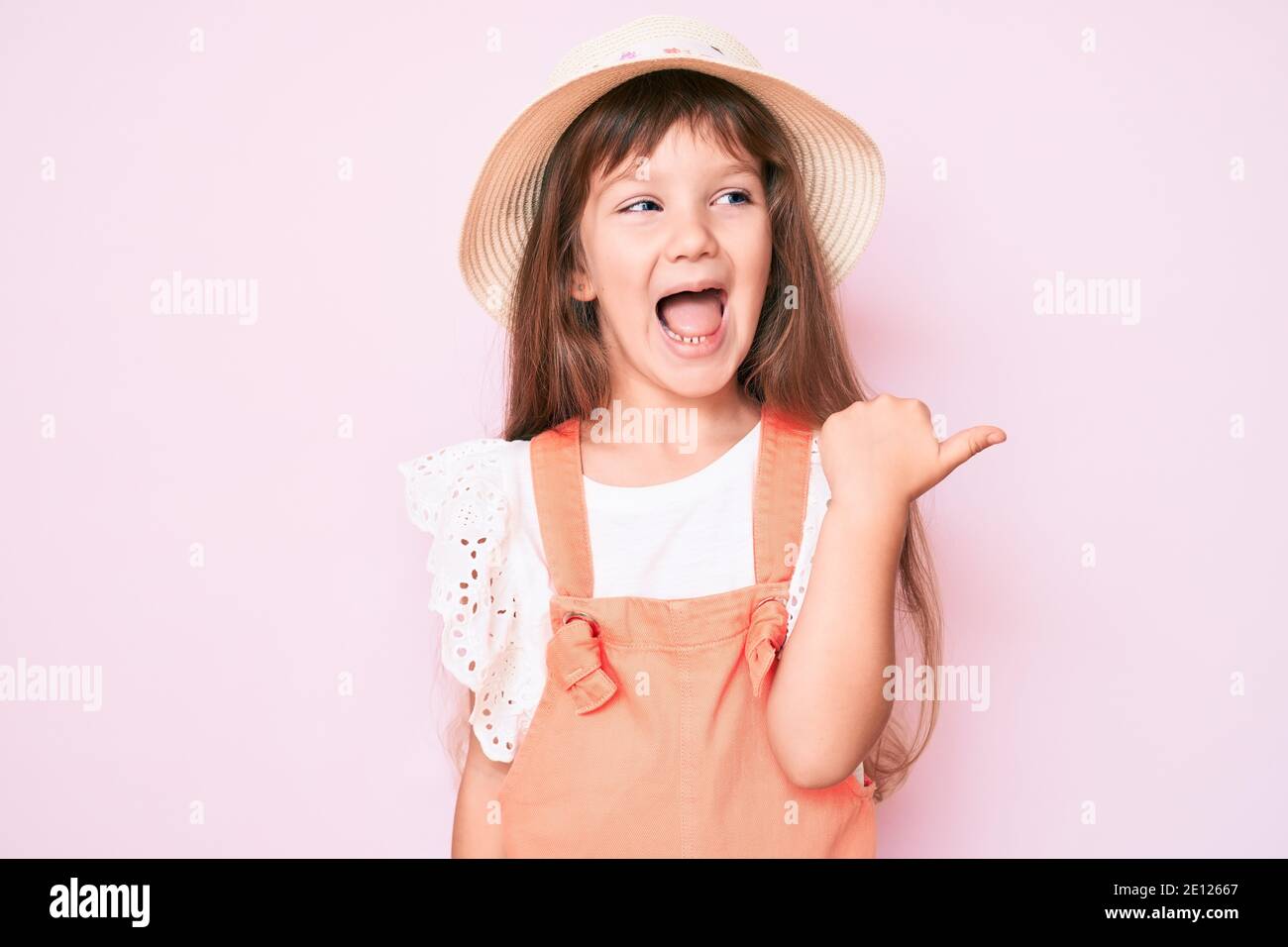 Little caucasian kid girl with long hair wearing spring hat pointing ...