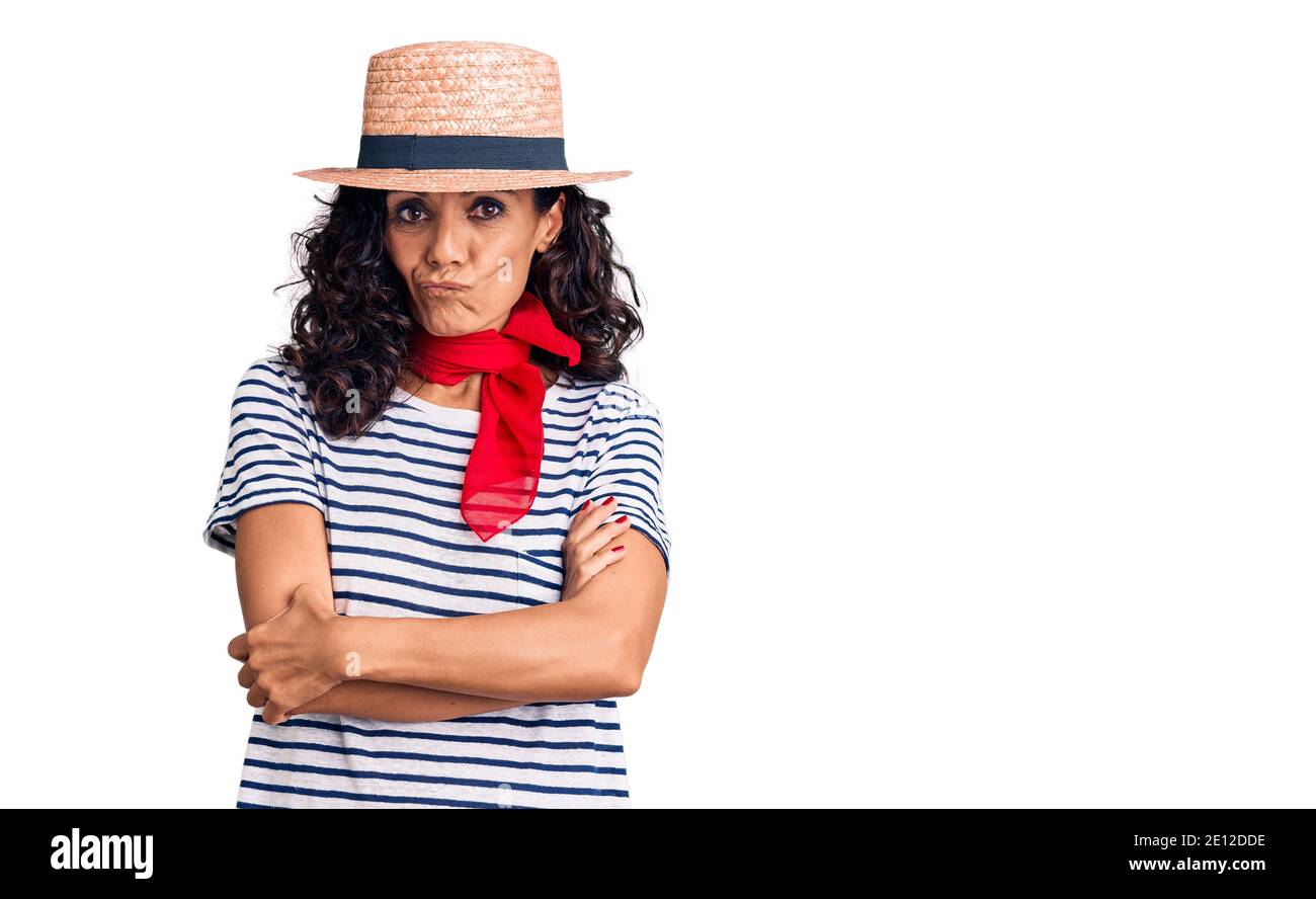 Middle age beautiful woman wearing casual striped t shirt and summer hat skeptic and nervous, disapproving expression on face with crossed arms. negat Stock Photo